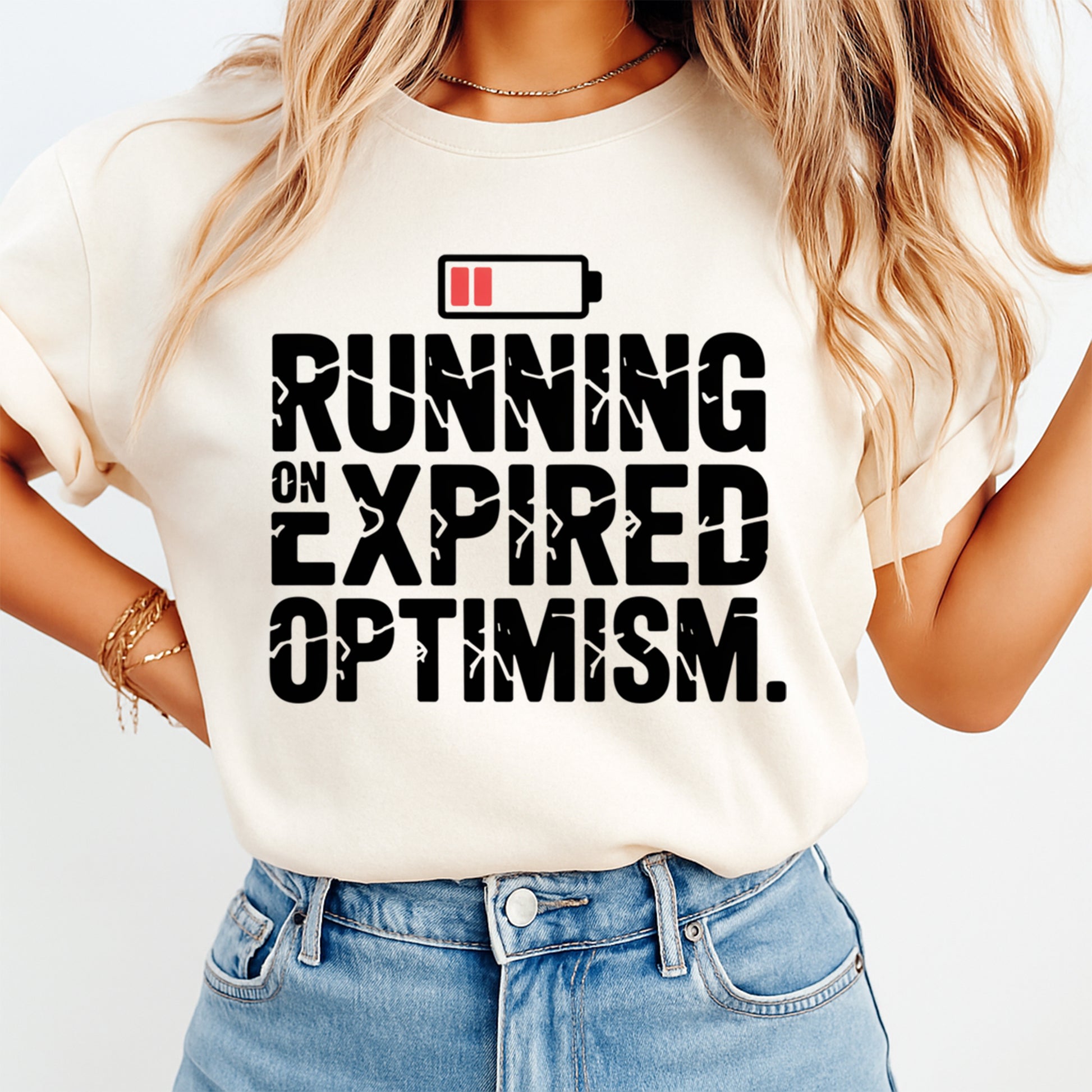 Funny sarcasm shirt mockup showing Running on Expired Optimism phrase with battery icon on light colored t shirt