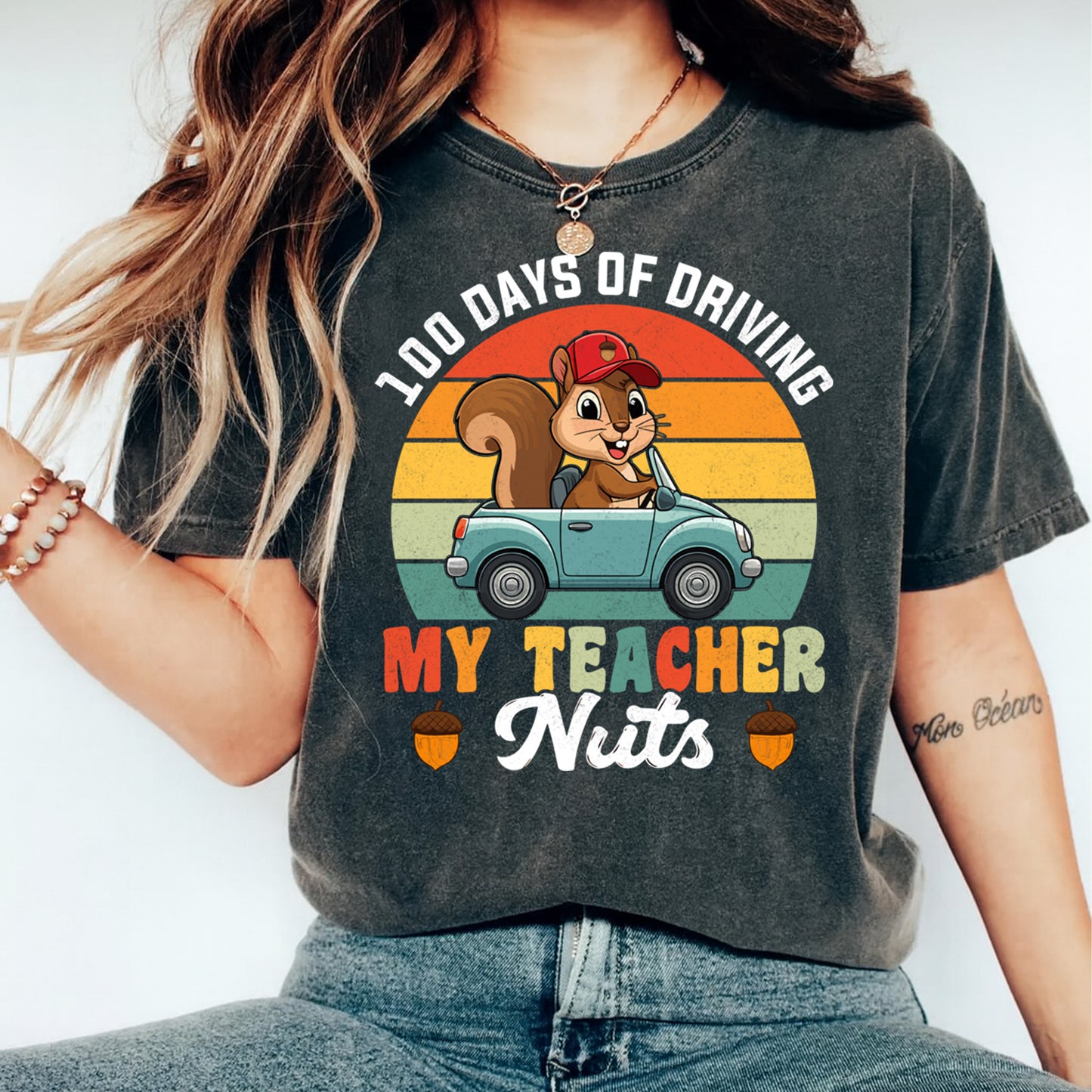 Woman wearing 100 days of driving my teacher nuts shirt with squirrel car graphic and retro sunset school design