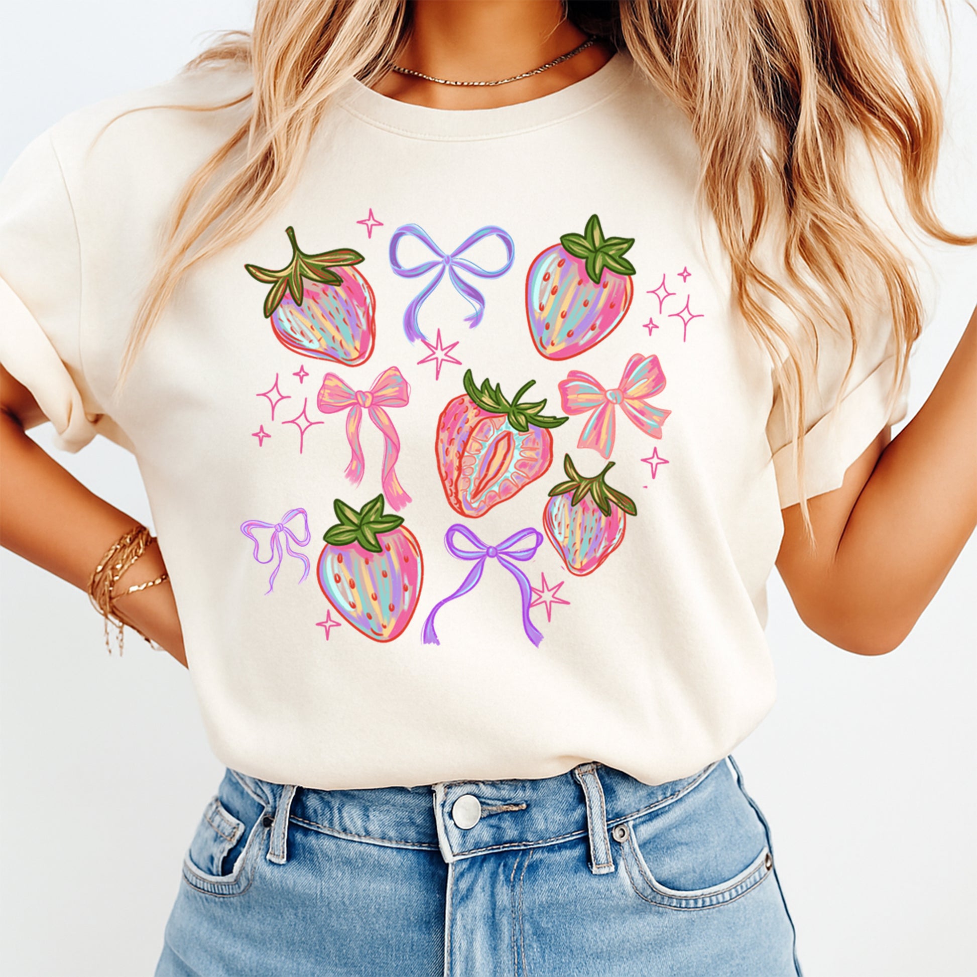 Woman wearing pastel strawberry bow shirt with colorful fruit and ribbon graphic