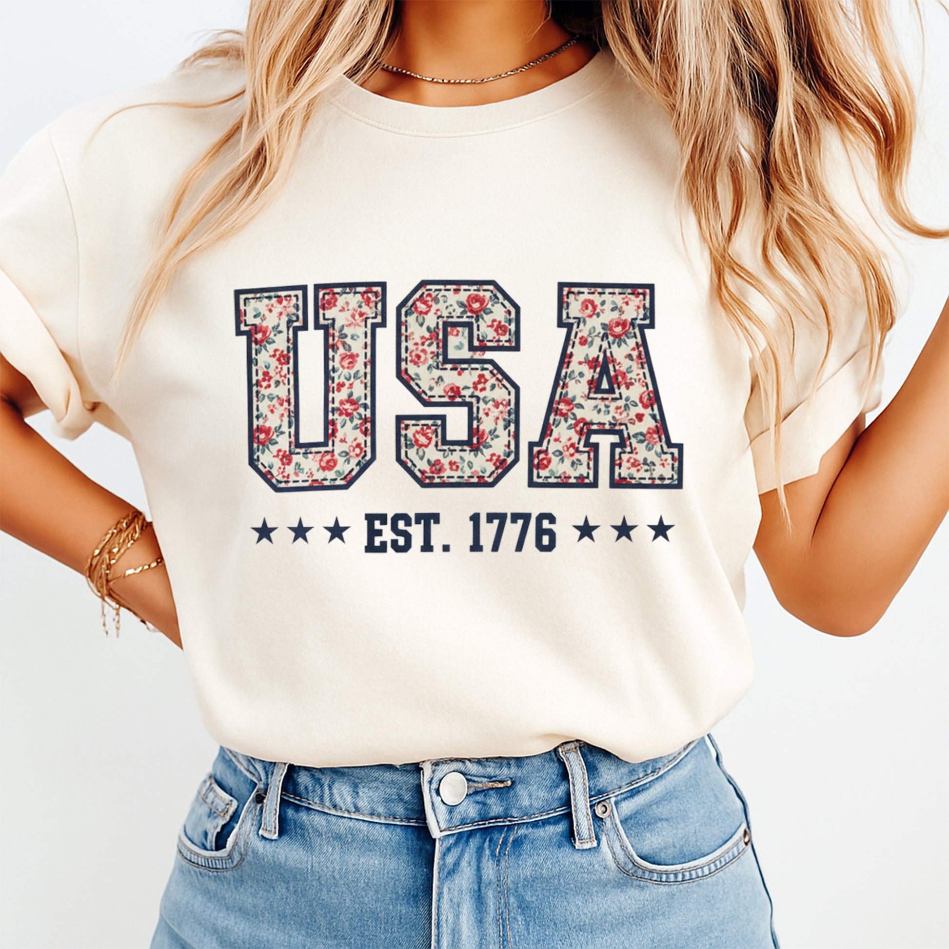 woman wearing beige shirt with usa est 1776 dtf transfer featuring floral filled letters and patriotic style