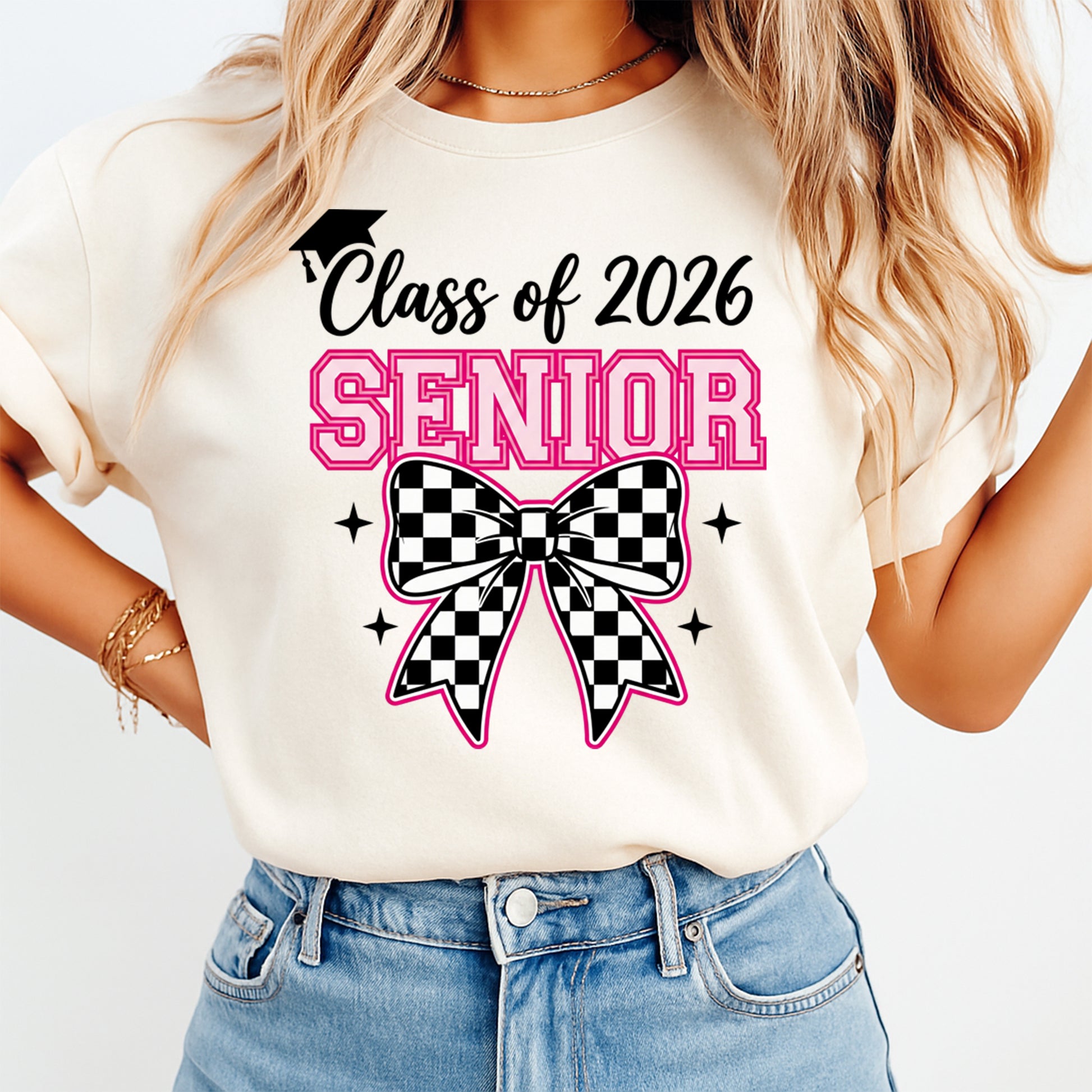 Woman wearing a cream shirt with class of 2026 senior checkerboard bow ready to press dtf graphic in pink varsity lettering