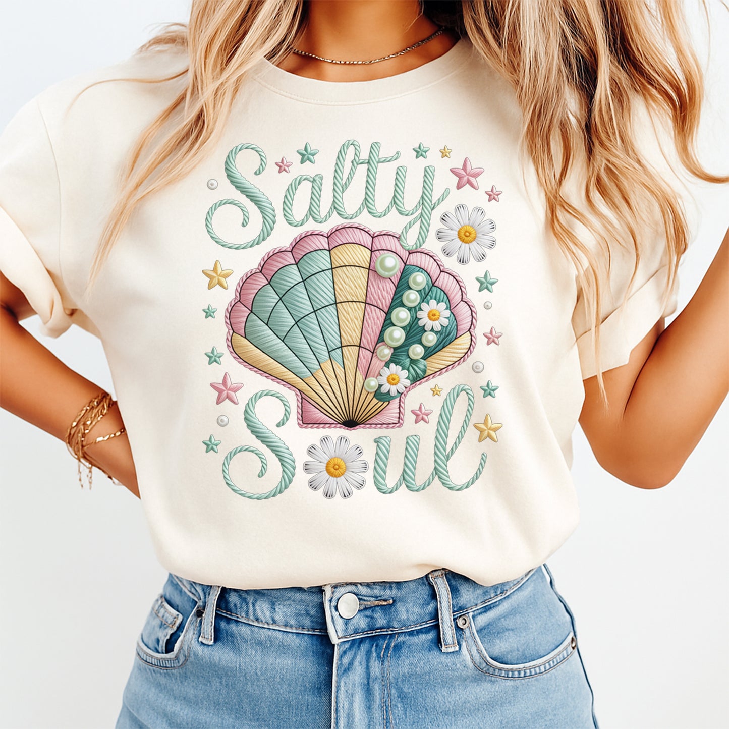 Woman wearing a cream shirt with salty soul ready to press dtf graphic featuring a pastel seashell pearls daisies and starfish