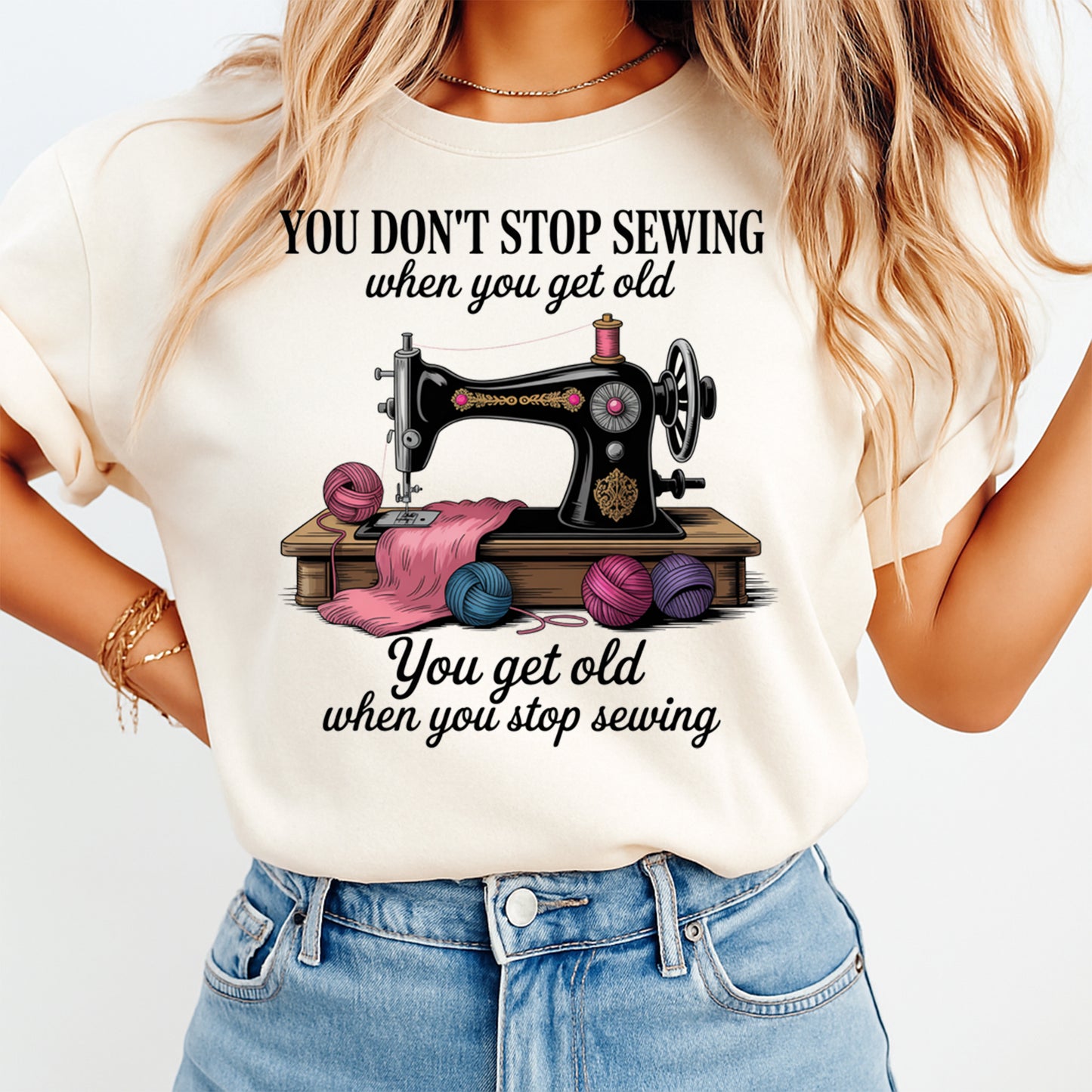 Woman wearing a cream shirt with you dont stop sewing when you get old ready to press dtf graphic featuring a vintage sewing machine and yarn