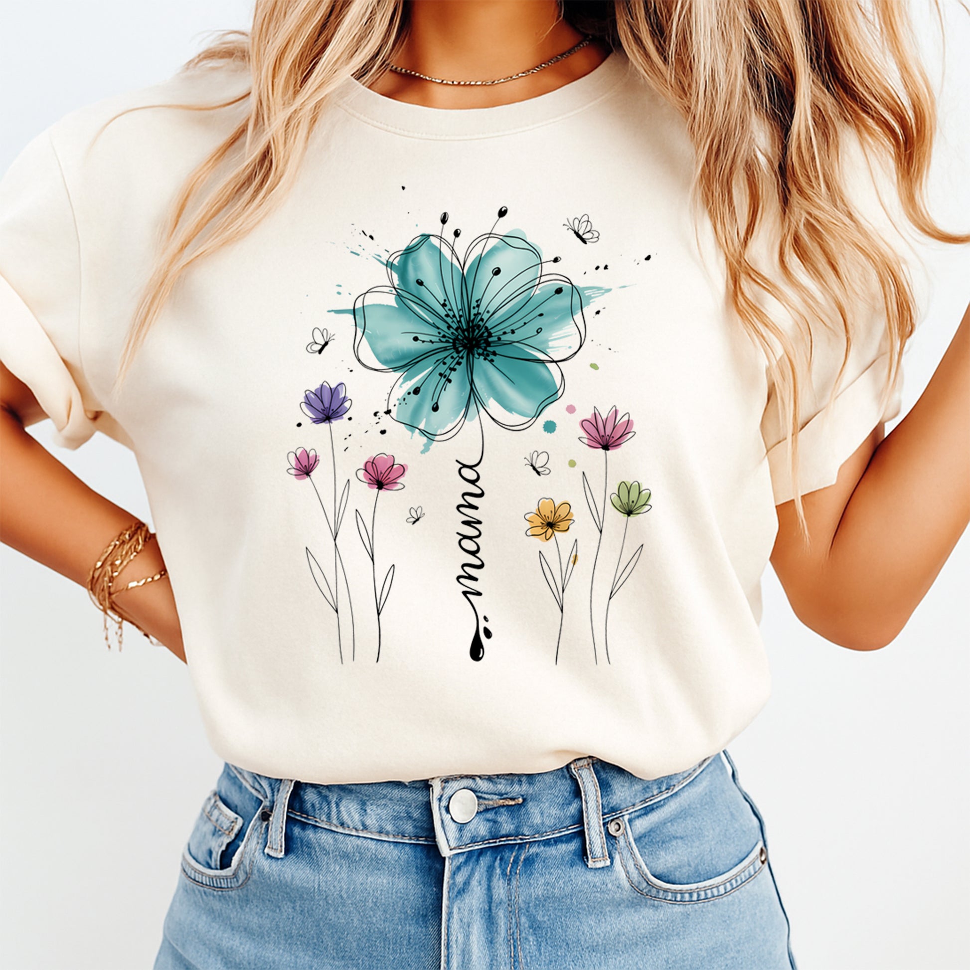 Woman wearing a cream shirt with mama ready to press dtf graphic featuring a large blue flower pastel wildflowers and butterfly accents