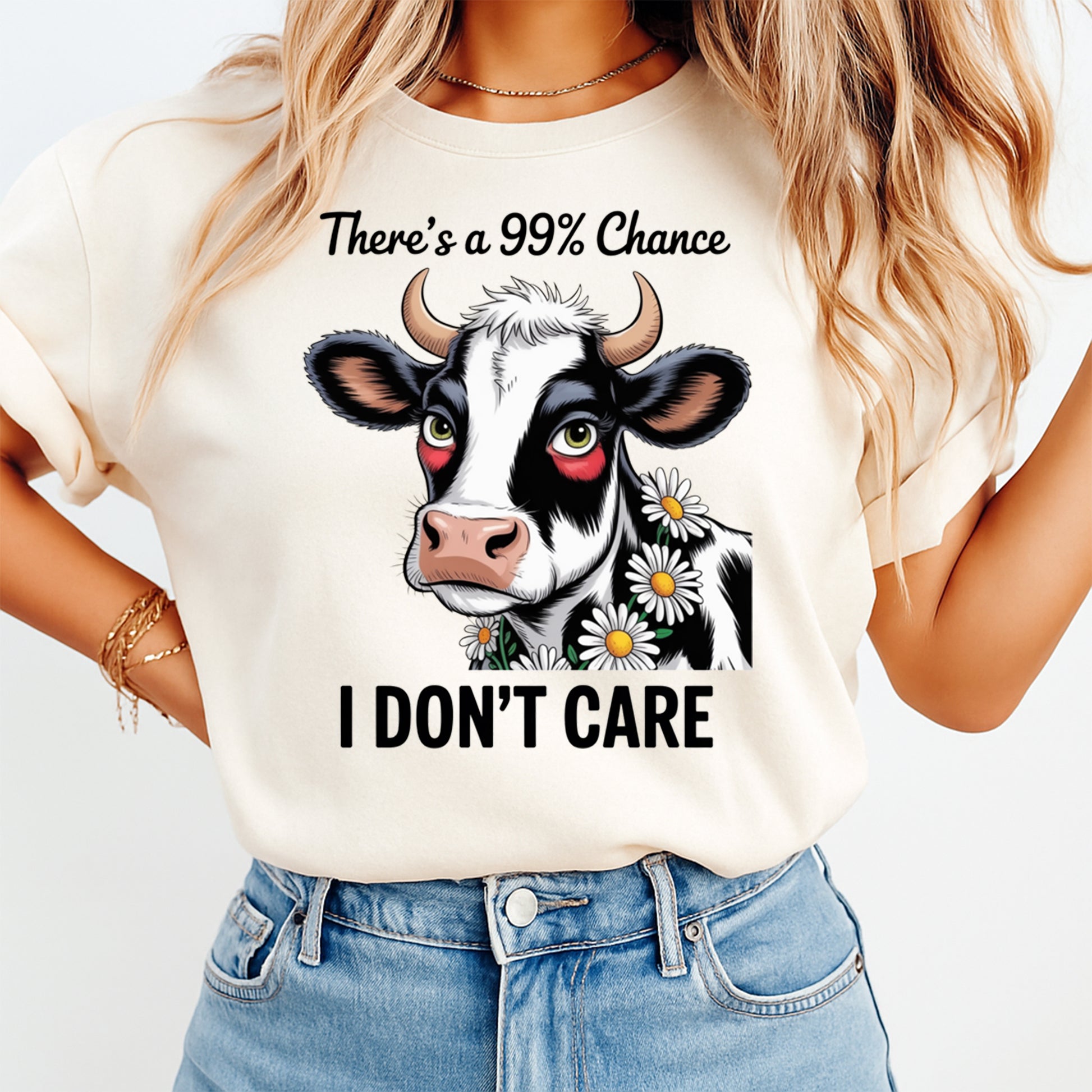 Woman wearing a cream shirt with a funny cow ready to press dtf graphic featuring daisies and There’s a 99% Chance I Don’t Care text