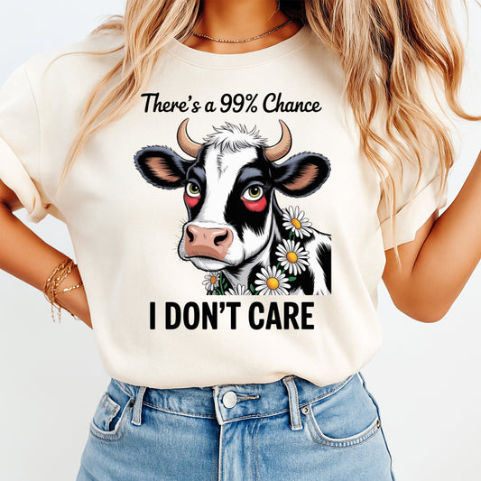 Woman wearing a cream shirt with a funny cow ready to press dtf graphic featuring daisies and There’s a 99% Chance I Don’t Care text