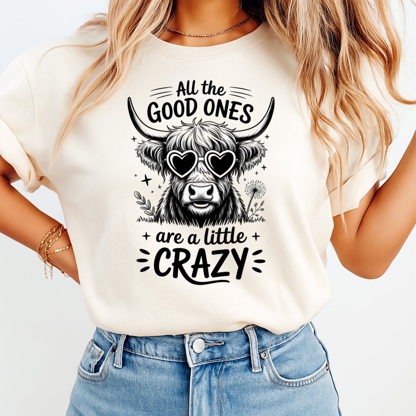 Mockup of a cream shirt featuring a funny western ready to press dtf transfer with a highland cow wearing heart sunglasses and the phrase All the good ones are a little crazy.