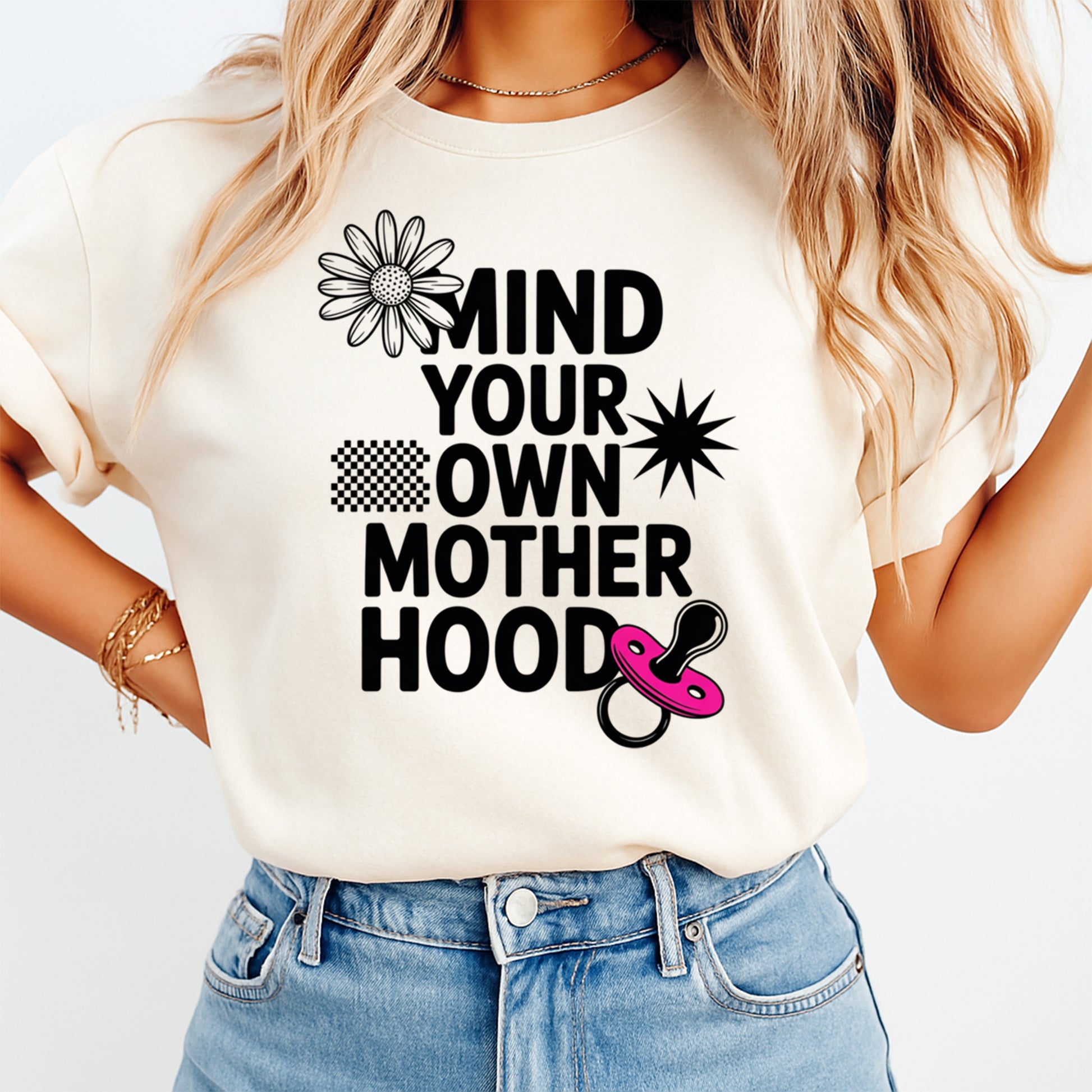 Mockup of a cream shirt featuring a funny mom ready to press dtf transfer with the phrase Mind Your Own Mother Hood, pink pacifier, daisy, and bold black text.