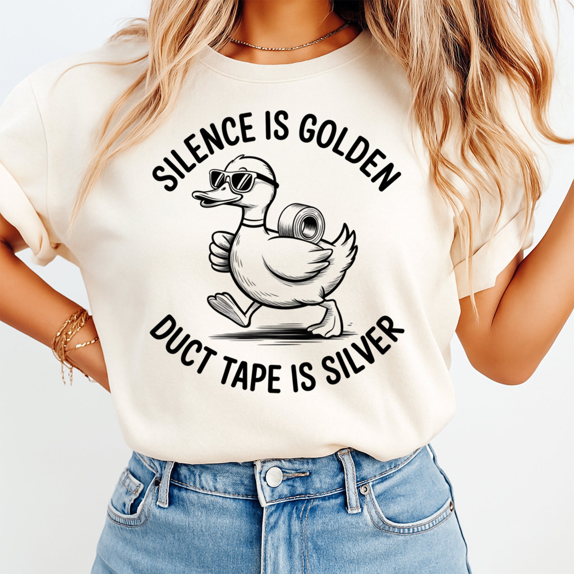 Mockup of a cream shirt featuring a funny duck ready to press dtf transfer with sunglasses, duct tape, and the phrase Silence is golden duct tape is silver.