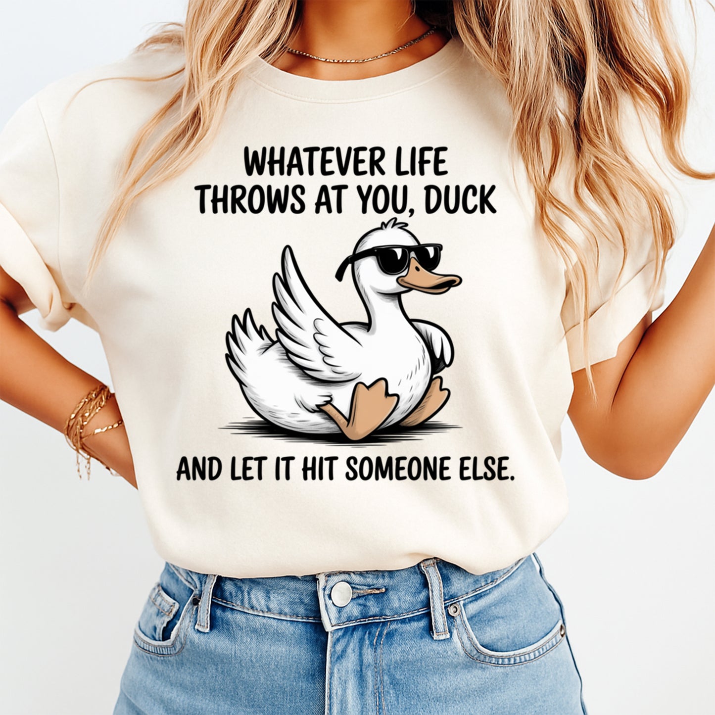 Mockup of a cream shirt featuring a funny duck ready to press dtf transfer with sunglasses and the phrase Whatever life throws at you, duck and let it hit someone else.
