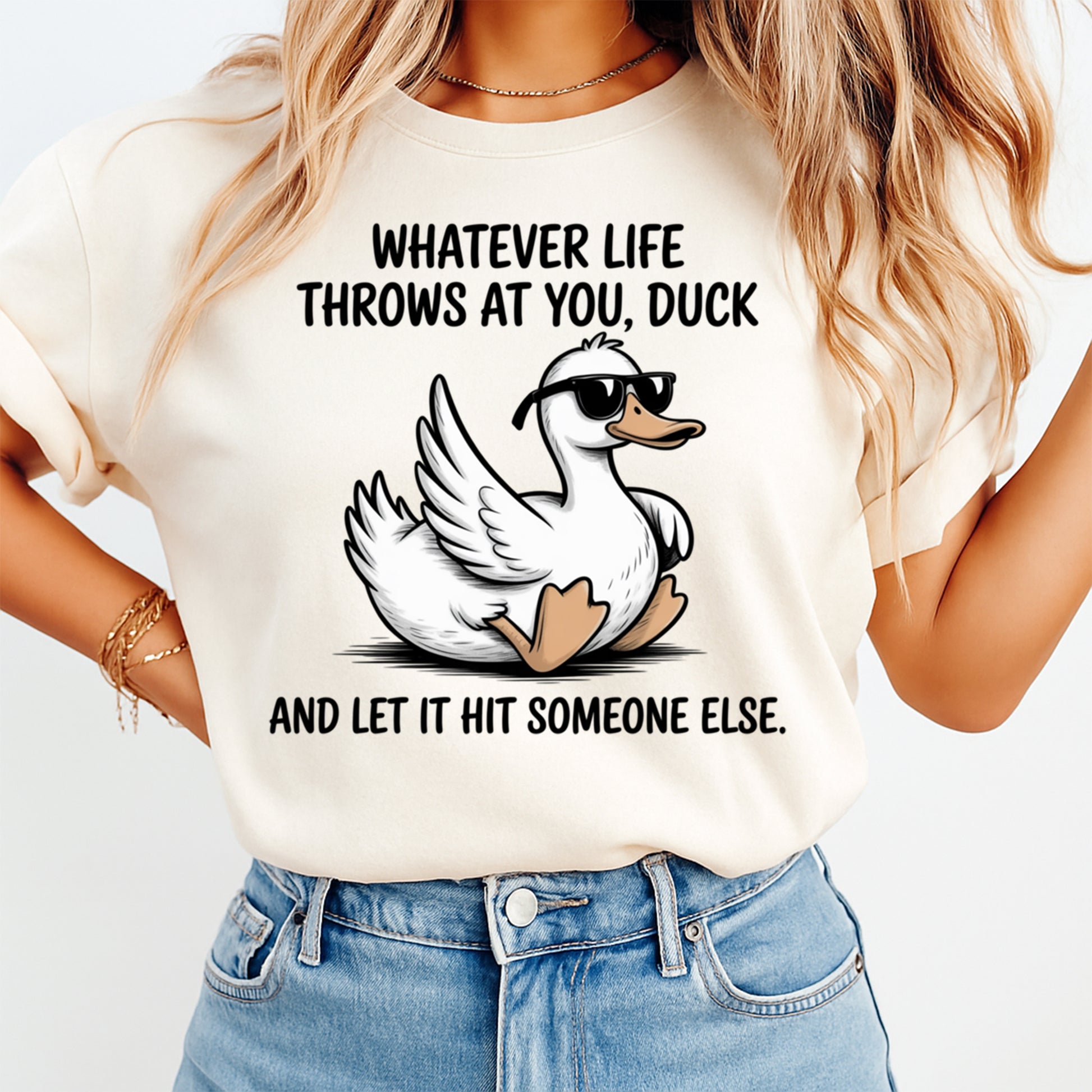 Mockup of a cream shirt featuring a funny duck ready to press dtf transfer with sunglasses and the phrase Whatever life throws at you, duck and let it hit someone else.