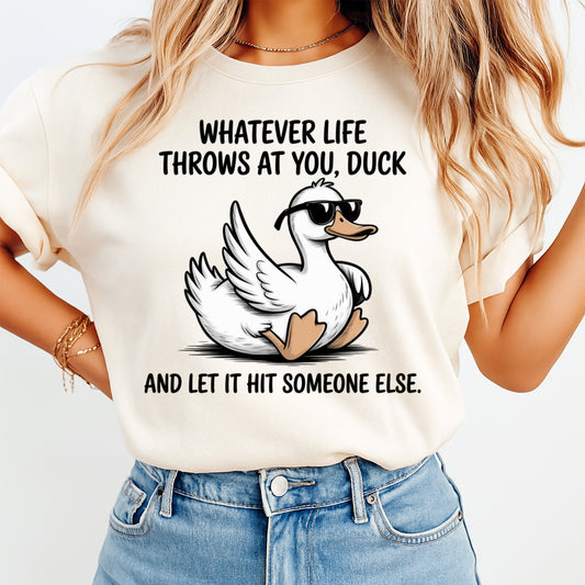 Mockup of a cream shirt featuring a funny duck ready to press dtf transfer with sunglasses and the phrase Whatever life throws at you, duck and let it hit someone else.