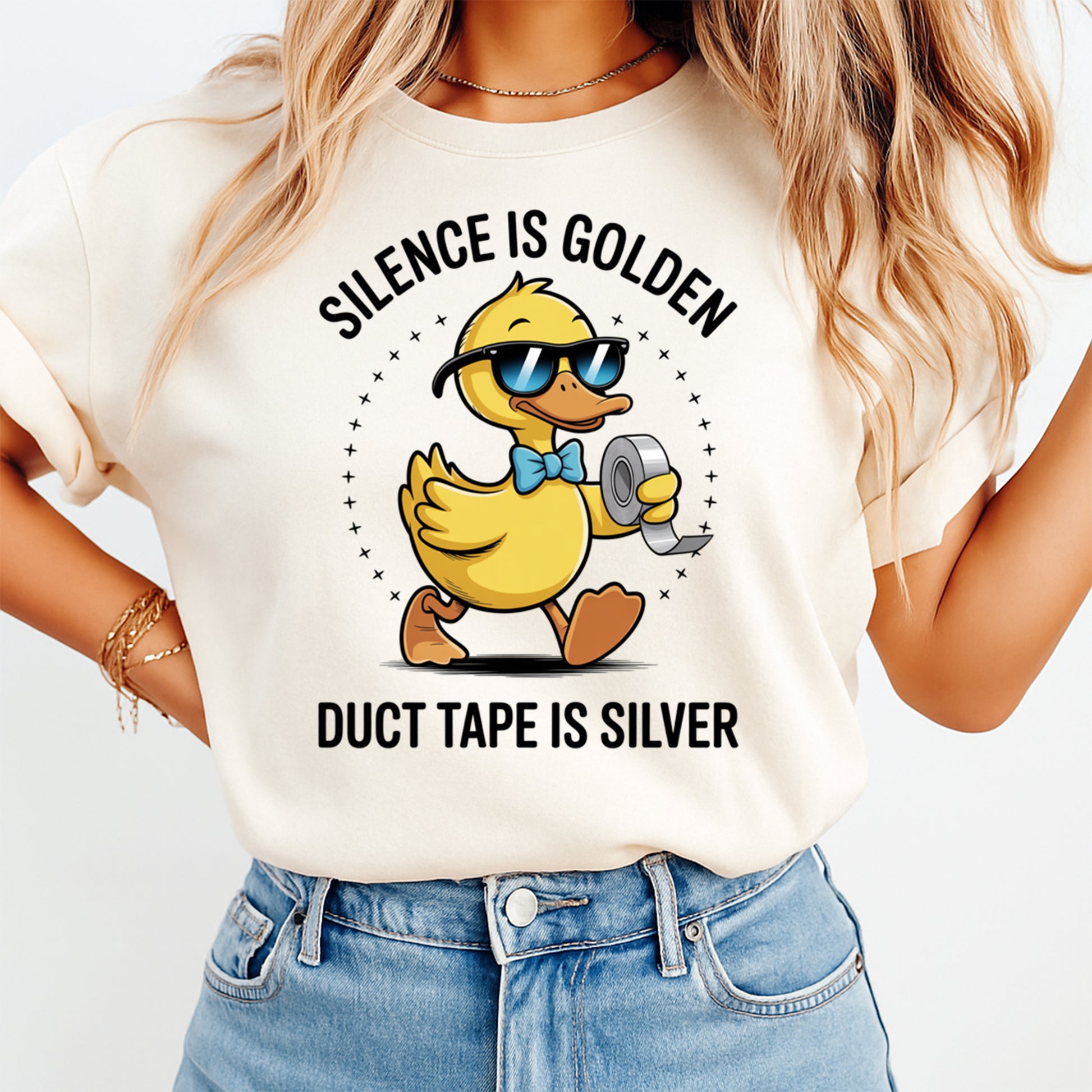 Mockup of a cream shirt featuring a funny duck ready to press dtf transfer with sunglasses, blue bow tie, duct tape, and the phrase Silence is Golden Duct Tape is Silver.