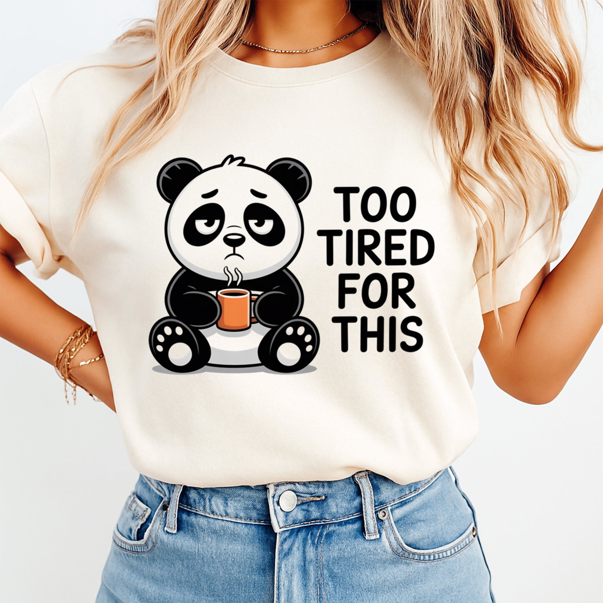 Mockup of a cream shirt featuring a funny panda ready to press dtf transfer with a tired panda holding a coffee mug and the phrase Too Tired For This.