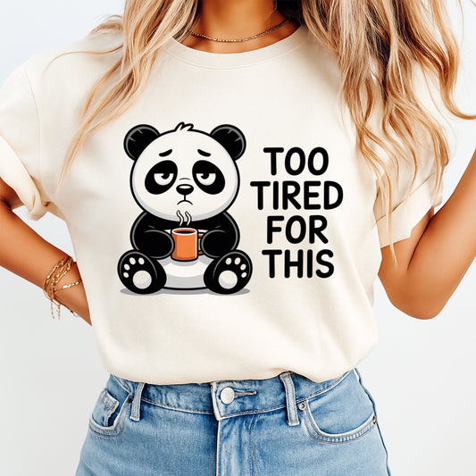Mockup of a cream shirt featuring a funny panda ready to press dtf transfer with a tired panda holding a coffee mug and the phrase Too Tired For This.