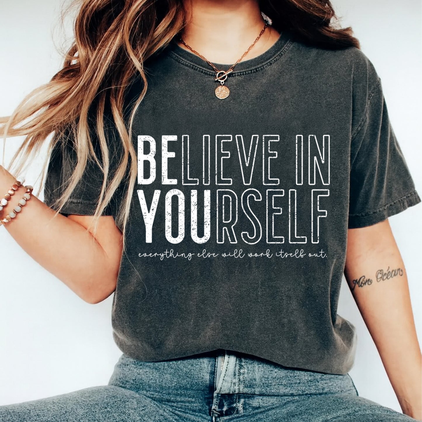 Mockup of a dark shirt featuring an inspirational ready to press dtf transfer with bold white Believe In Yourself lettering and small motivational quote text.