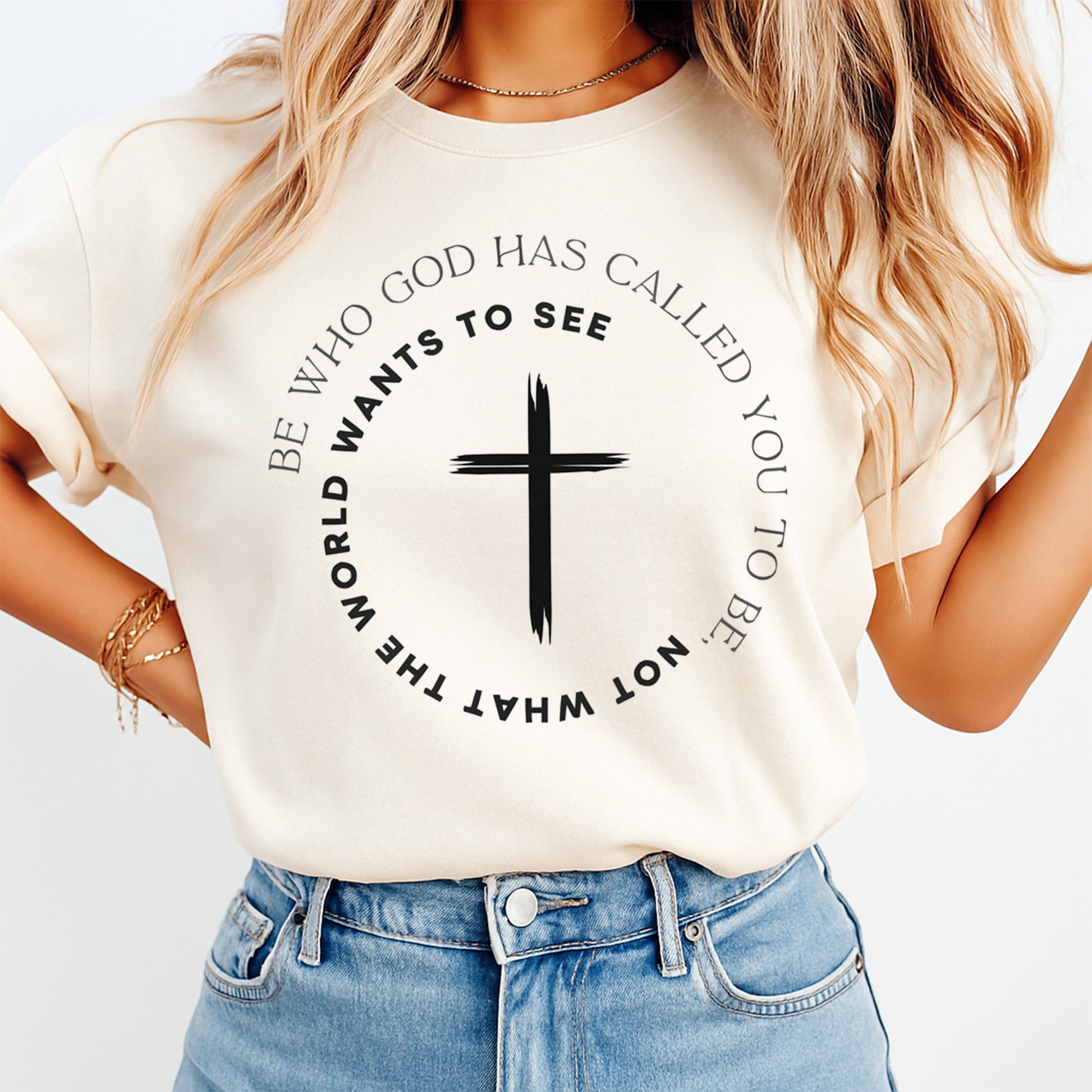 Mockup of a cream shirt featuring a Christian ready to press dtf transfer with a black cross and the phrase Be who God has called you to be not what the world wants to see.