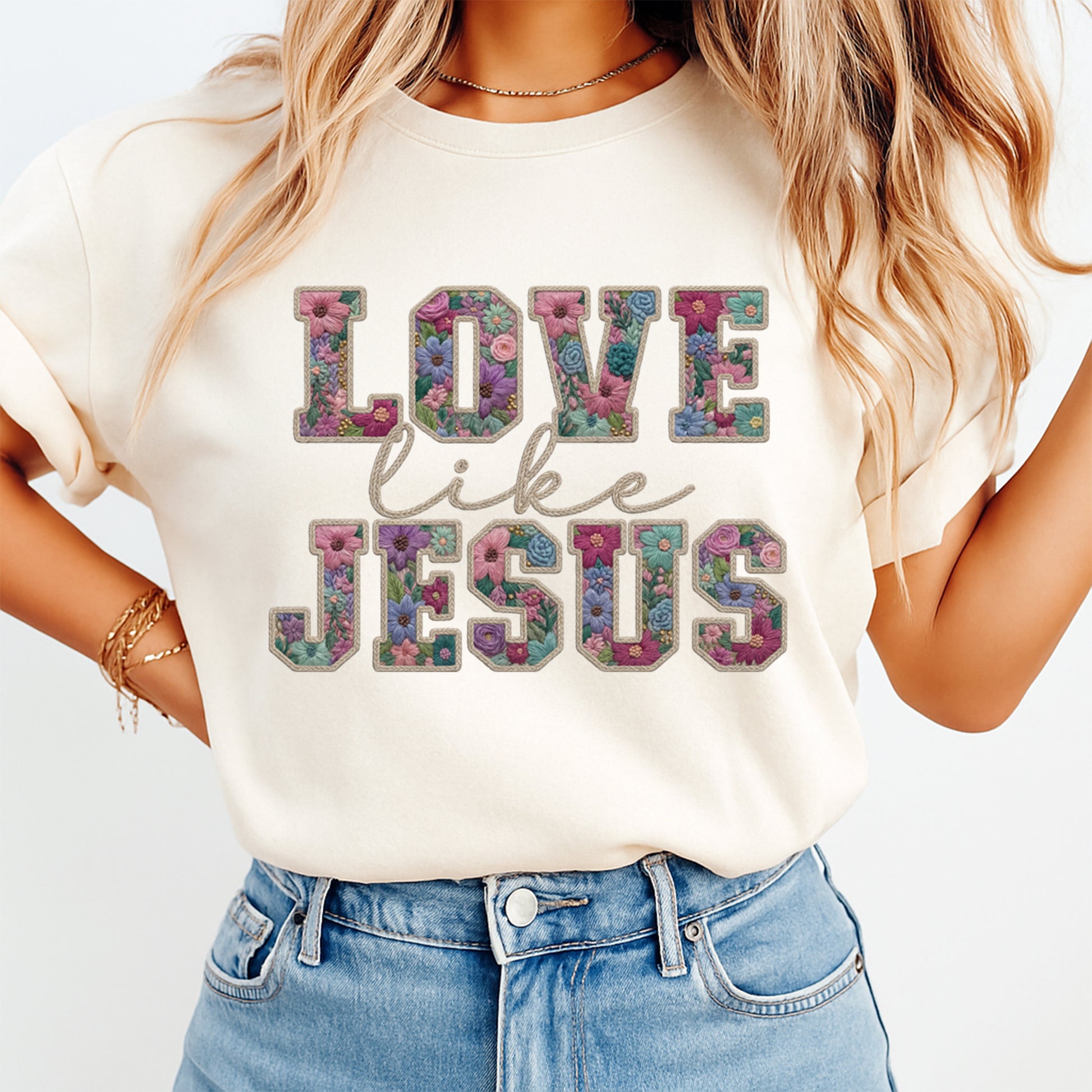Mockup of a cream shirt featuring a Christian floral ready to press dtf transfer with the phrase Love Like Jesus in embroidered-style floral lettering.