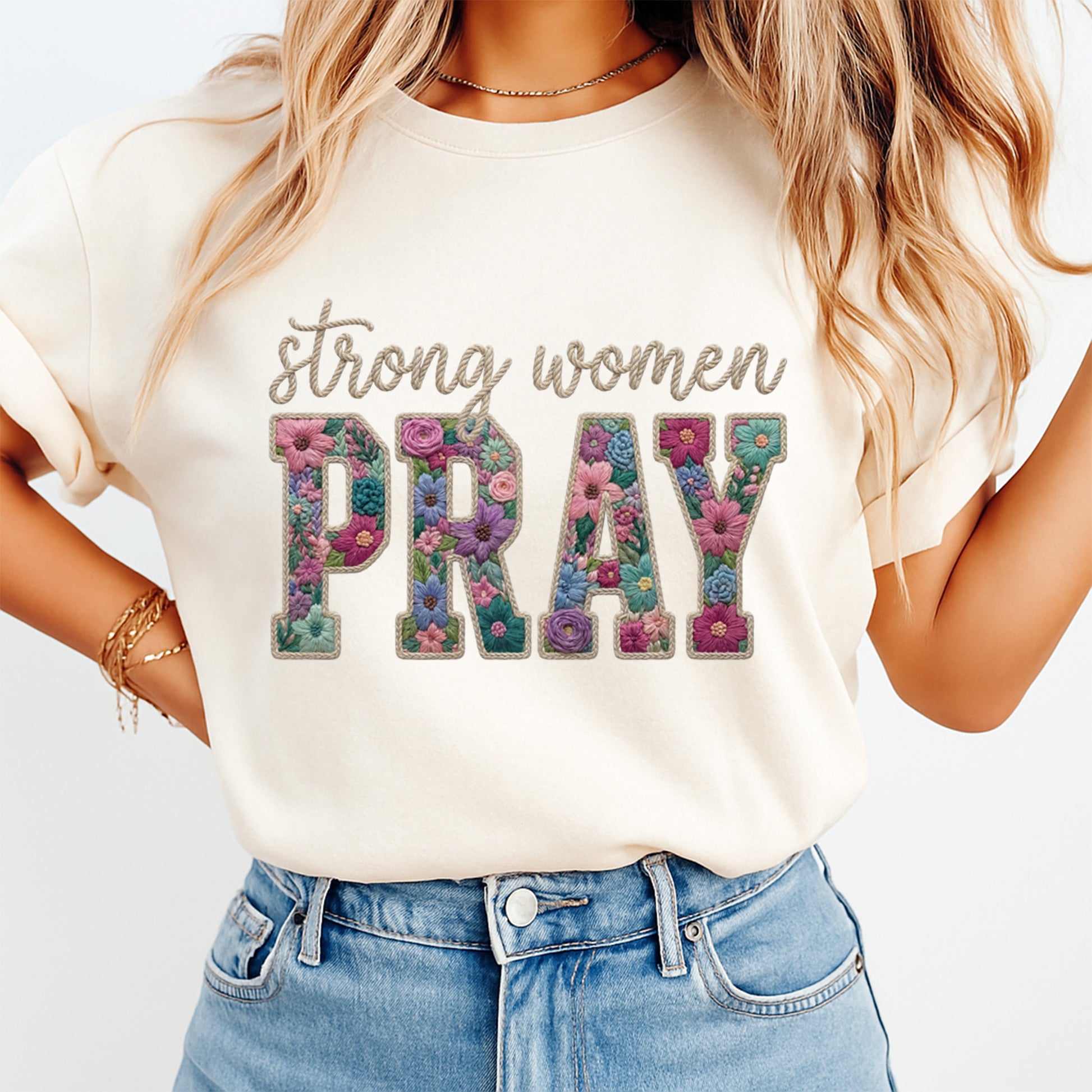 Mockup of a cream shirt featuring a Christian floral ready to press dtf transfer with the phrase Strong Women Pray in embroidered-style floral lettering.