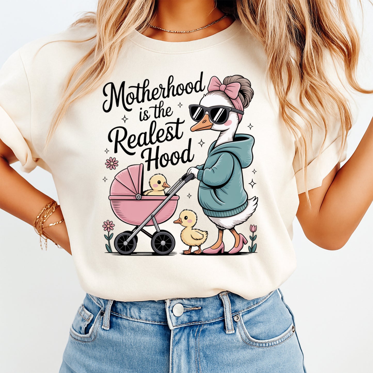 Cream shirt mockup featuring a funny motherhood ready to press dtf transfer with a stylish goose mom pushing a stroller and the phrase Motherhood is the Realest Hood.