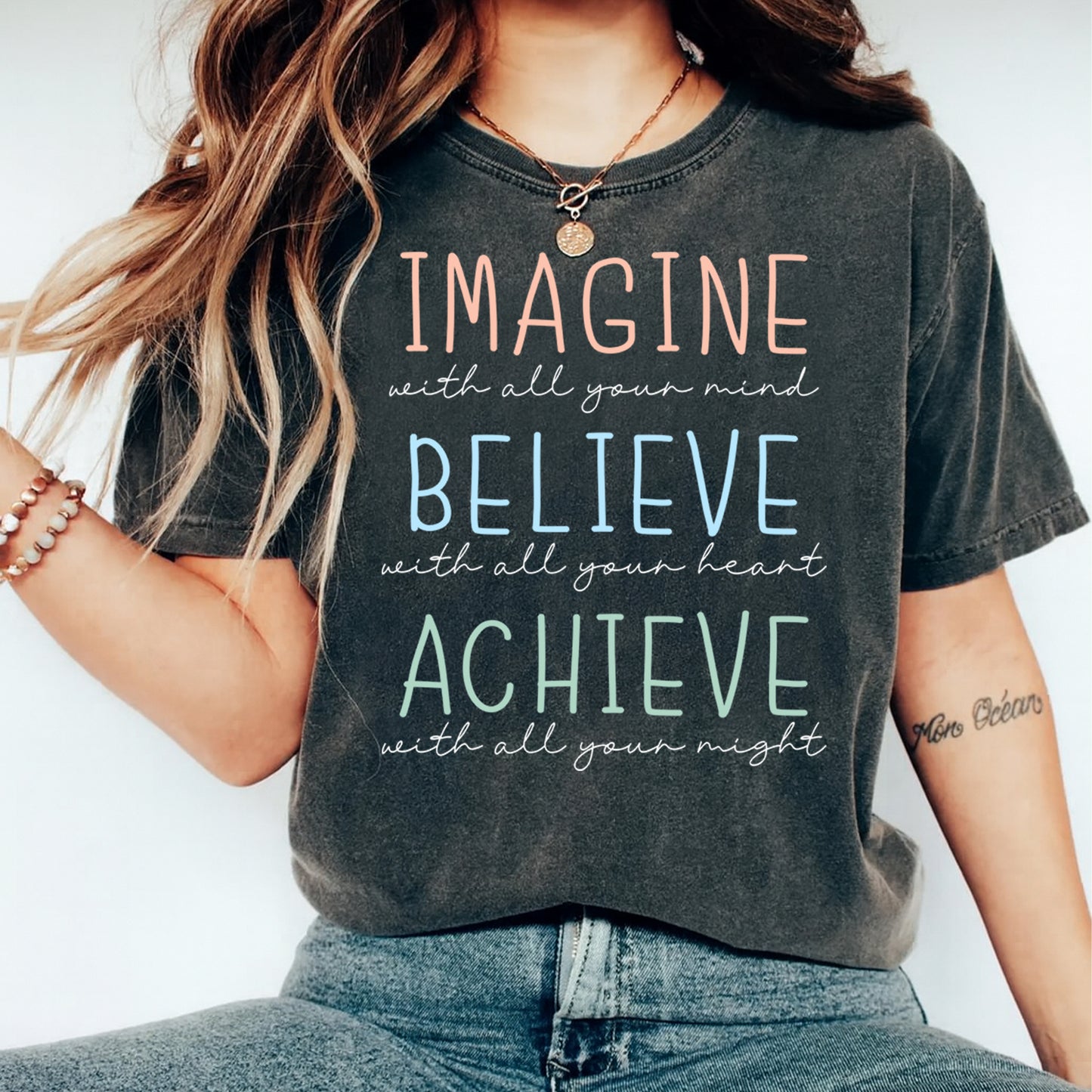 Black shirt mockup featuring a motivational ready to press dtf transfer with the phrase Imagine Believe Achieve in soft pastel lettering.