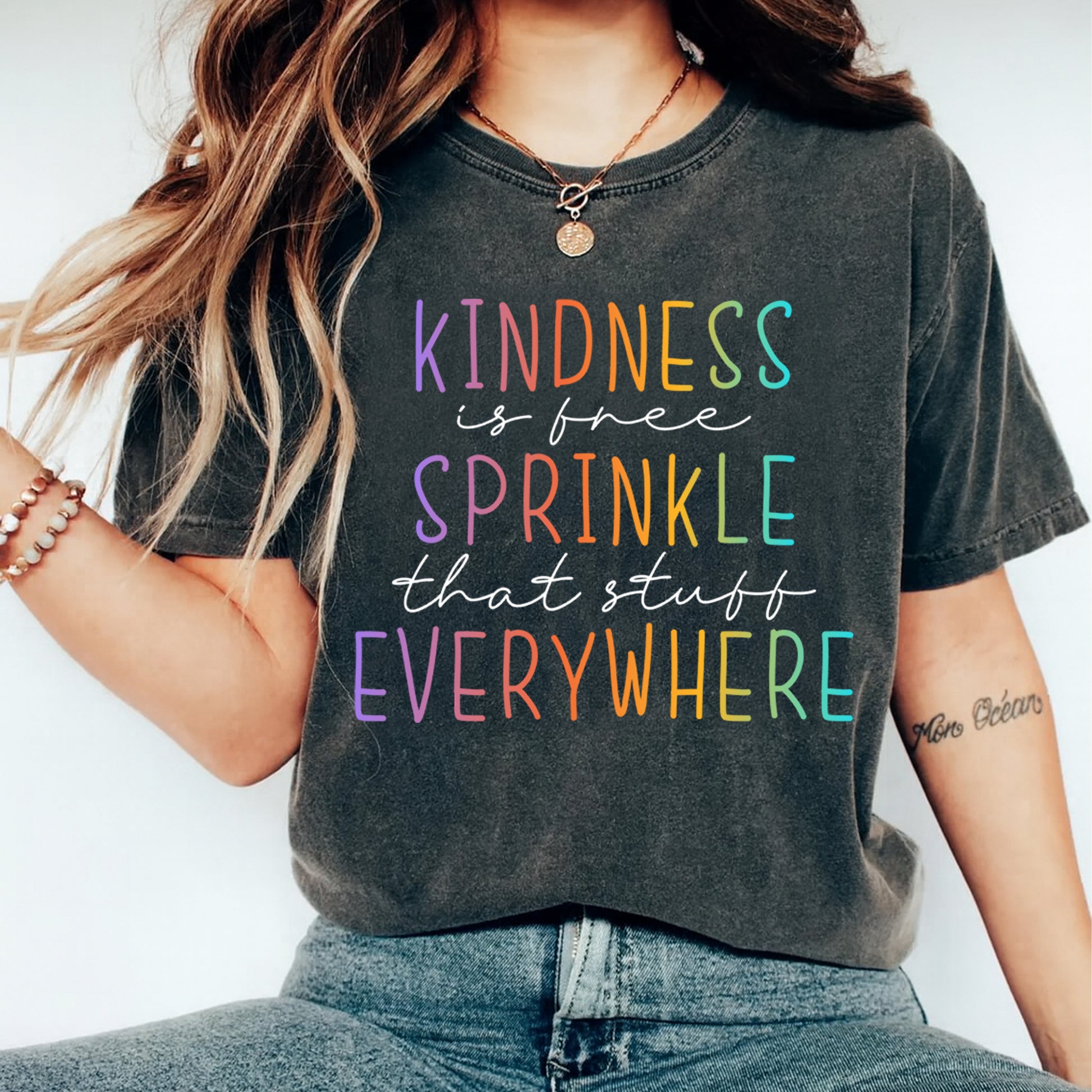 Black shirt mockup featuring a colorful kindness ready to press dtf transfer with the phrase Kindness is free Sprinkle that stuff Everywhere.