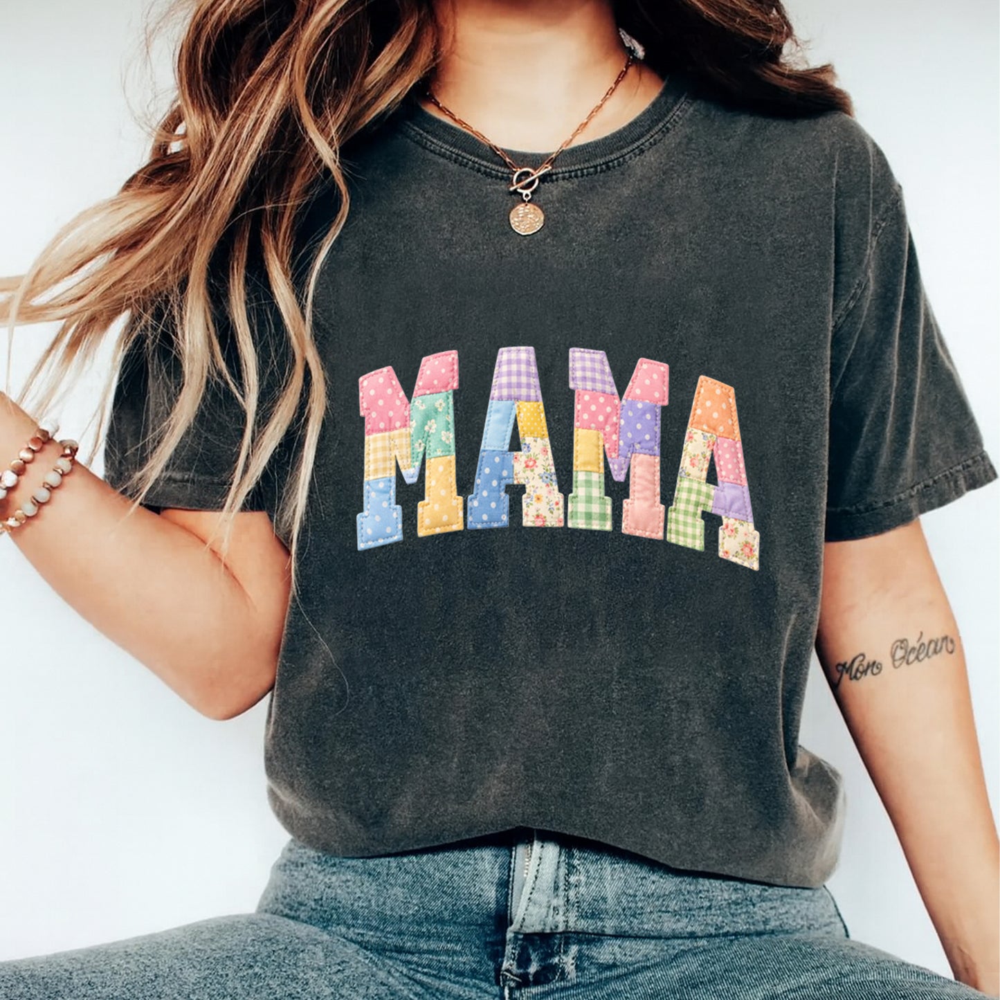 Black shirt mockup featuring a colorful Mama ready to press dtf transfer with patchwork-style lettering, floral accents, and pastel fabric-inspired patterns.