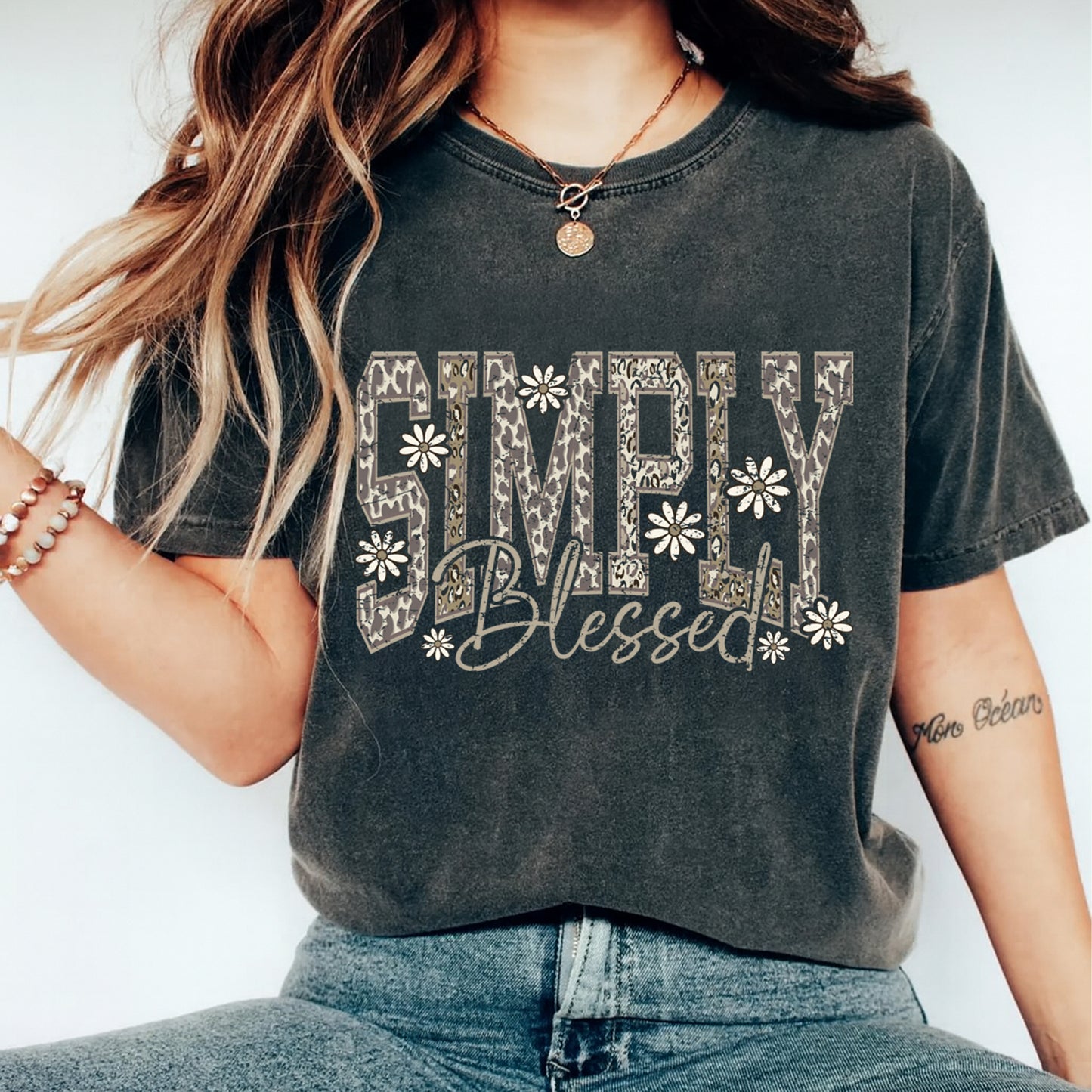 Lifestyle mockup of a black shirt with a faith inspired ready to press dtf graphic that says Simply Blessed with floral accents.