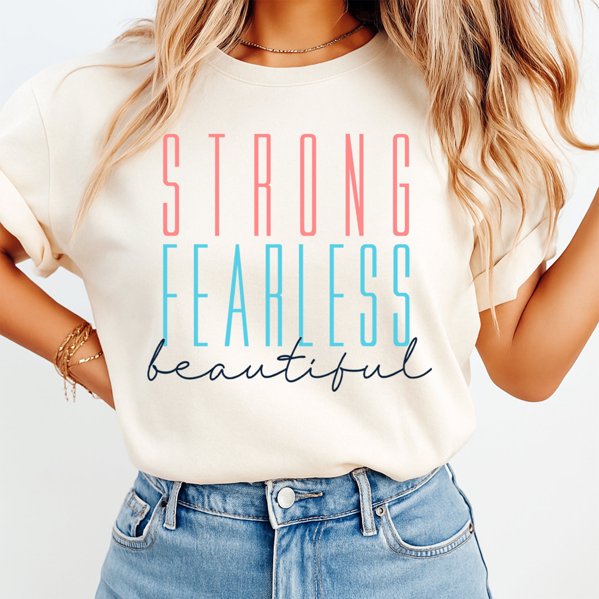 Lifestyle mockup of a cream shirt with an inspirational ready to press dtf graphic that says Strong Fearless Beautiful.