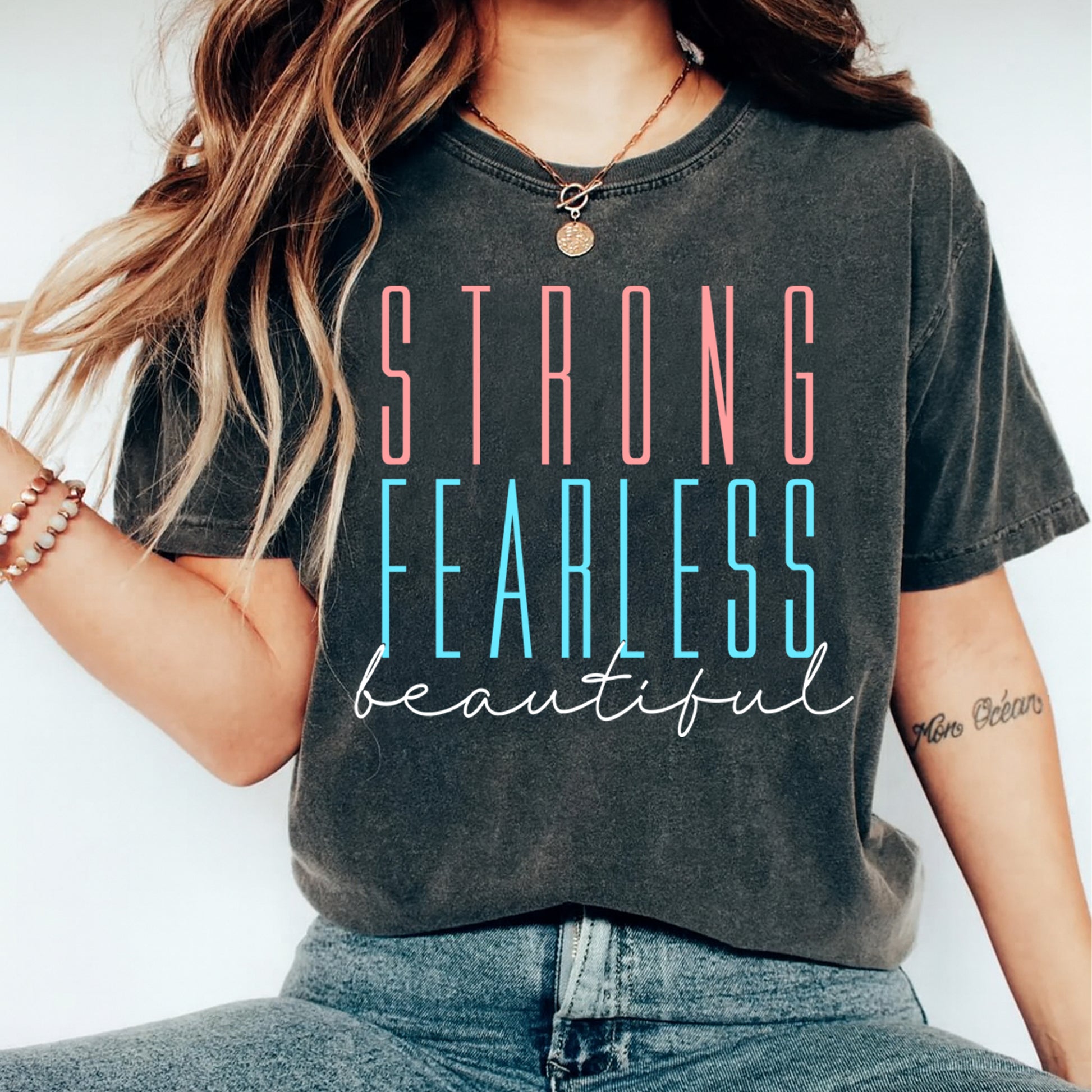 Person wearing a t-shirt with 'STRONG FEARLESS beautiful' text on a plain background