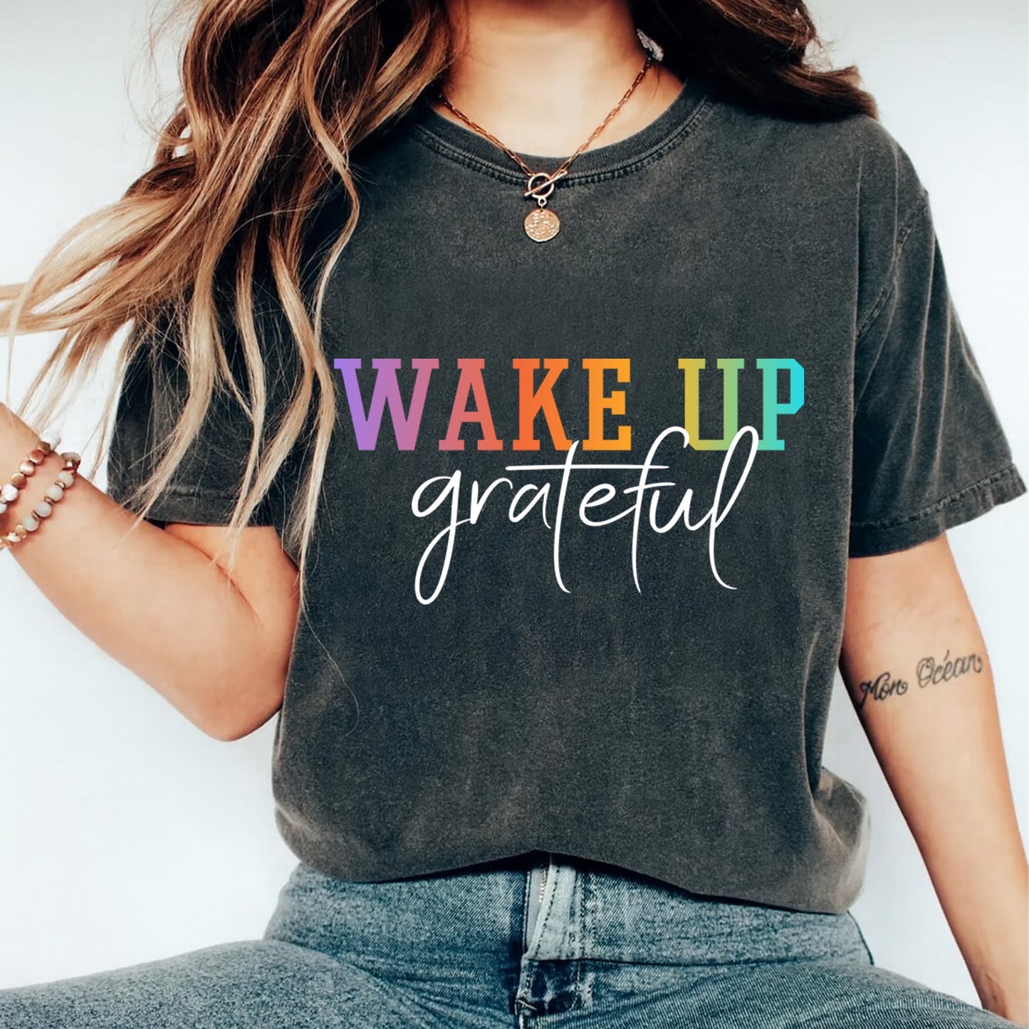 Lifestyle mockup of a black shirt with an inspirational ready to press dtf graphic that says Wake Up Grateful.