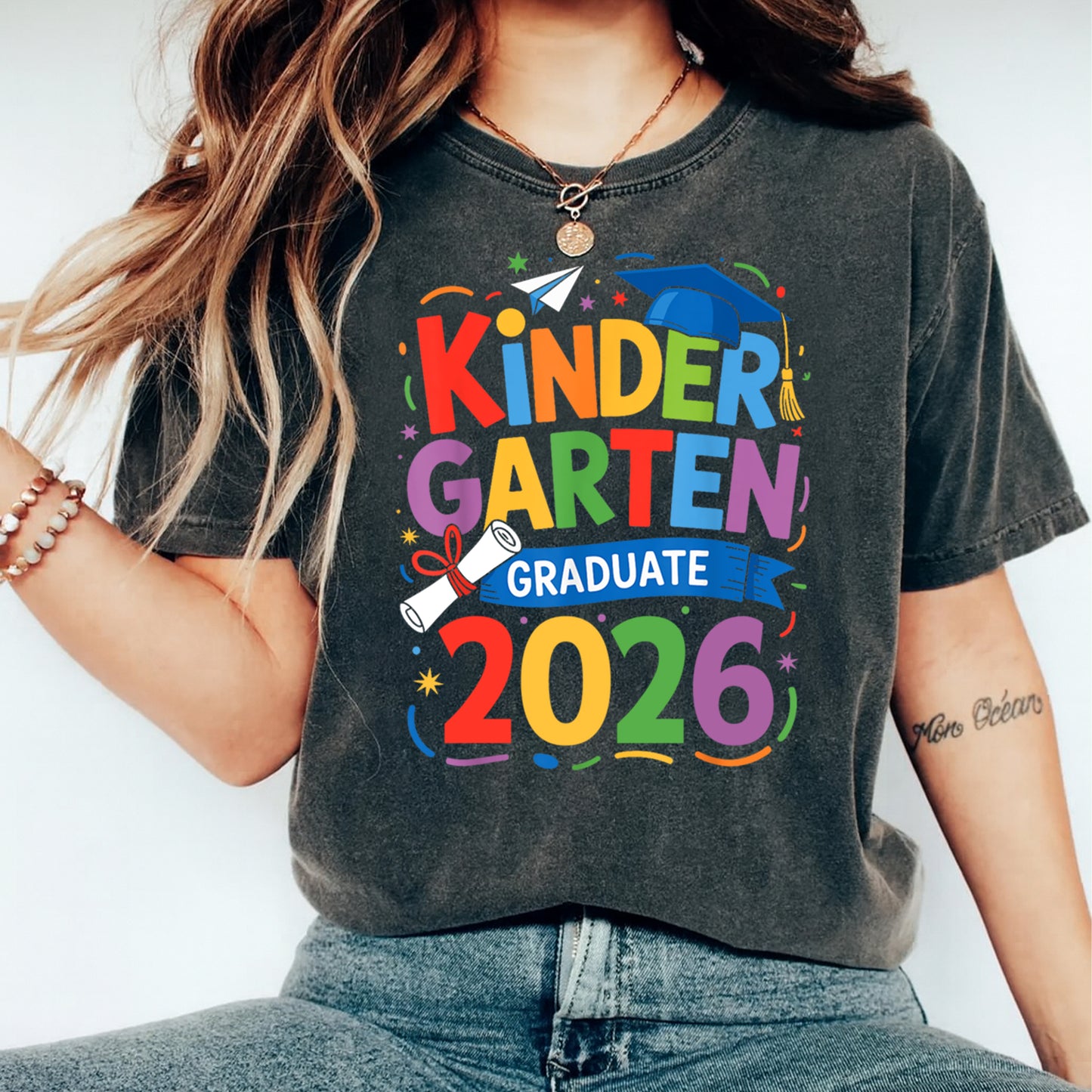 Mockup of black shirt featuring Kindergarten Graduate 2026 ready to press dtf transfer with colorful graduation cap, diploma, and school celebration artwork.
