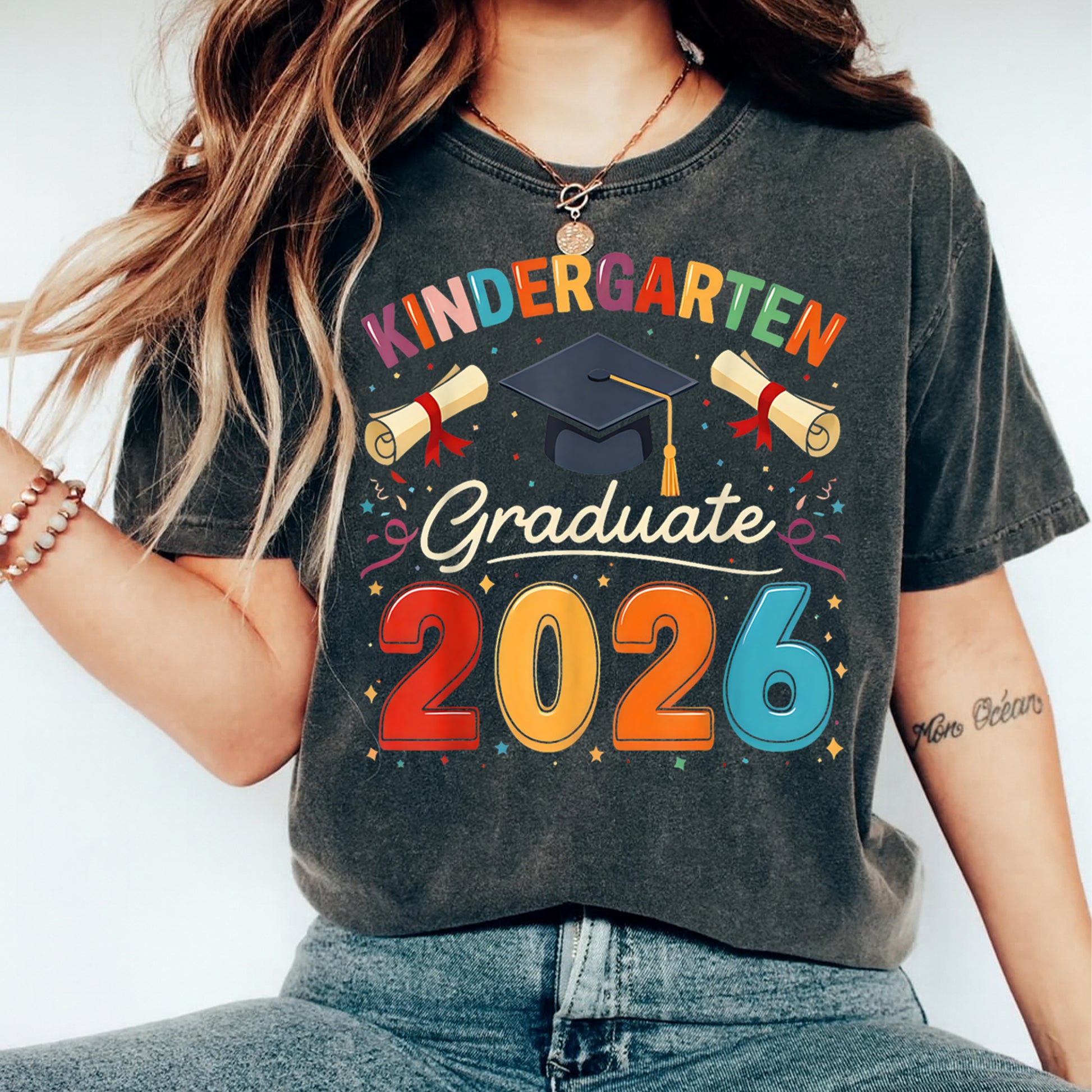 Mockup of black shirt featuring Kindergarten Graduate 2026 ready to press dtf transfer with colorful graduation cap, diplomas, and celebration artwork.