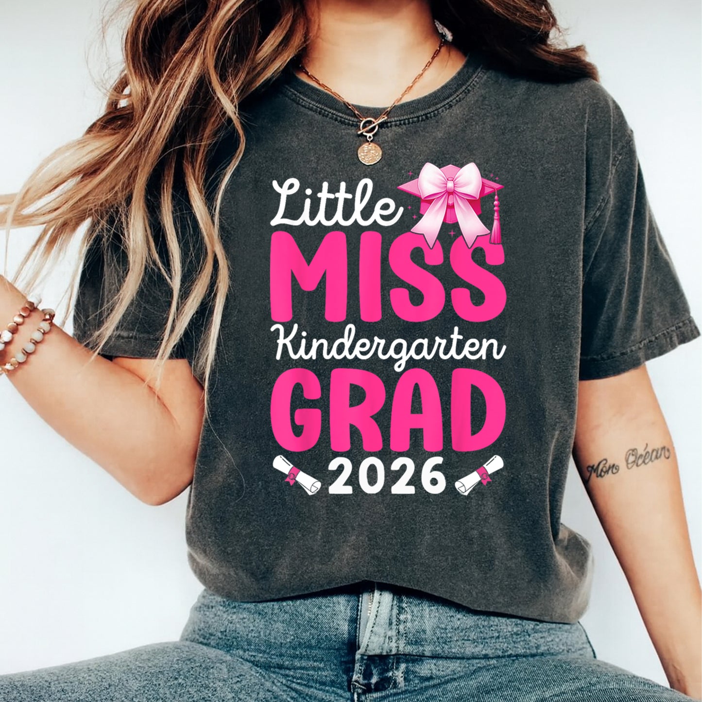 Black shirt mockup featuring a pink kindergarten grad 2026 ready to press dtf transfer with bow, graduation cap, and diploma accents.