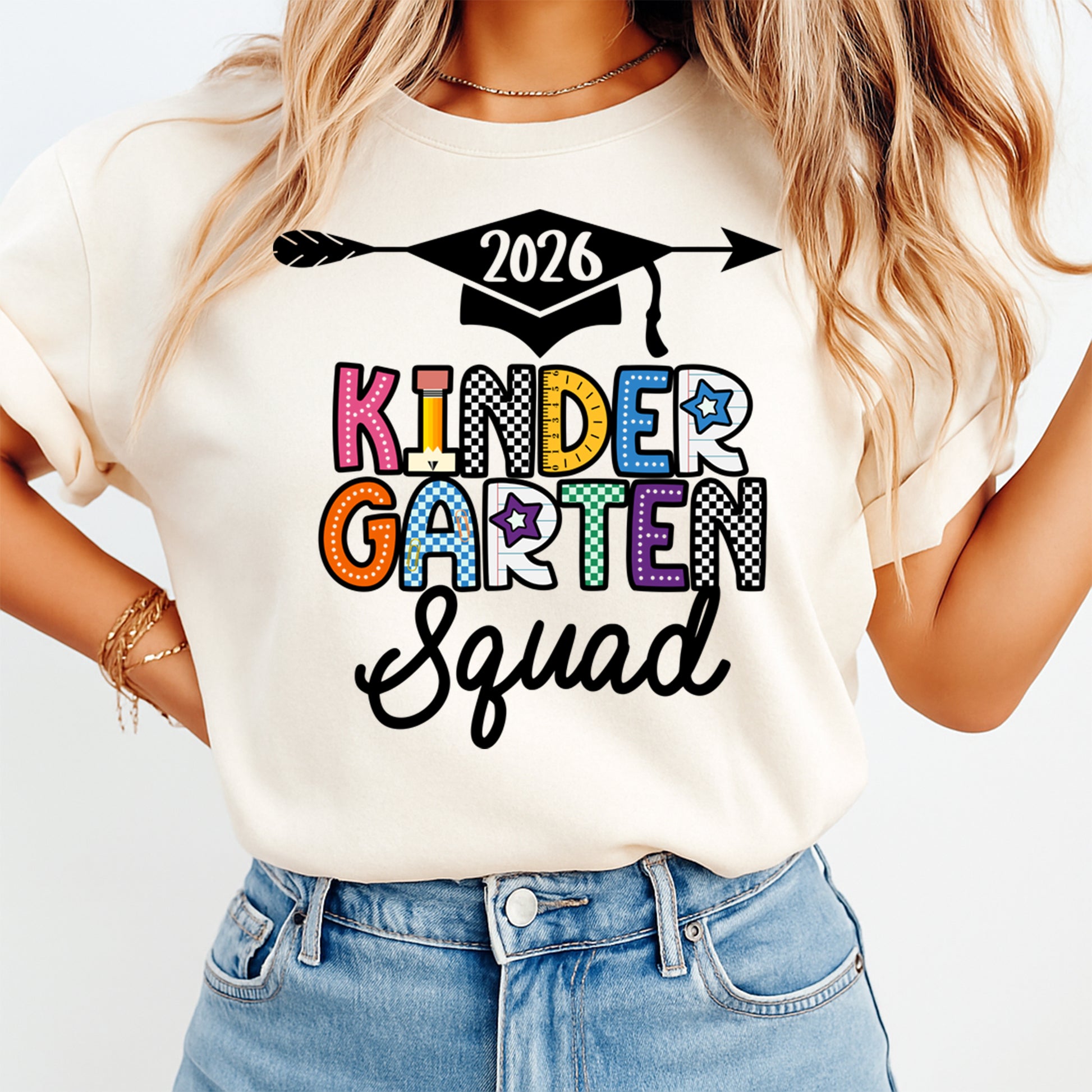 Cream shirt mockup featuring a Kinder Garten Squad 2026 ready to press dtf transfer with graduation cap, arrow, and colorful school lettering.