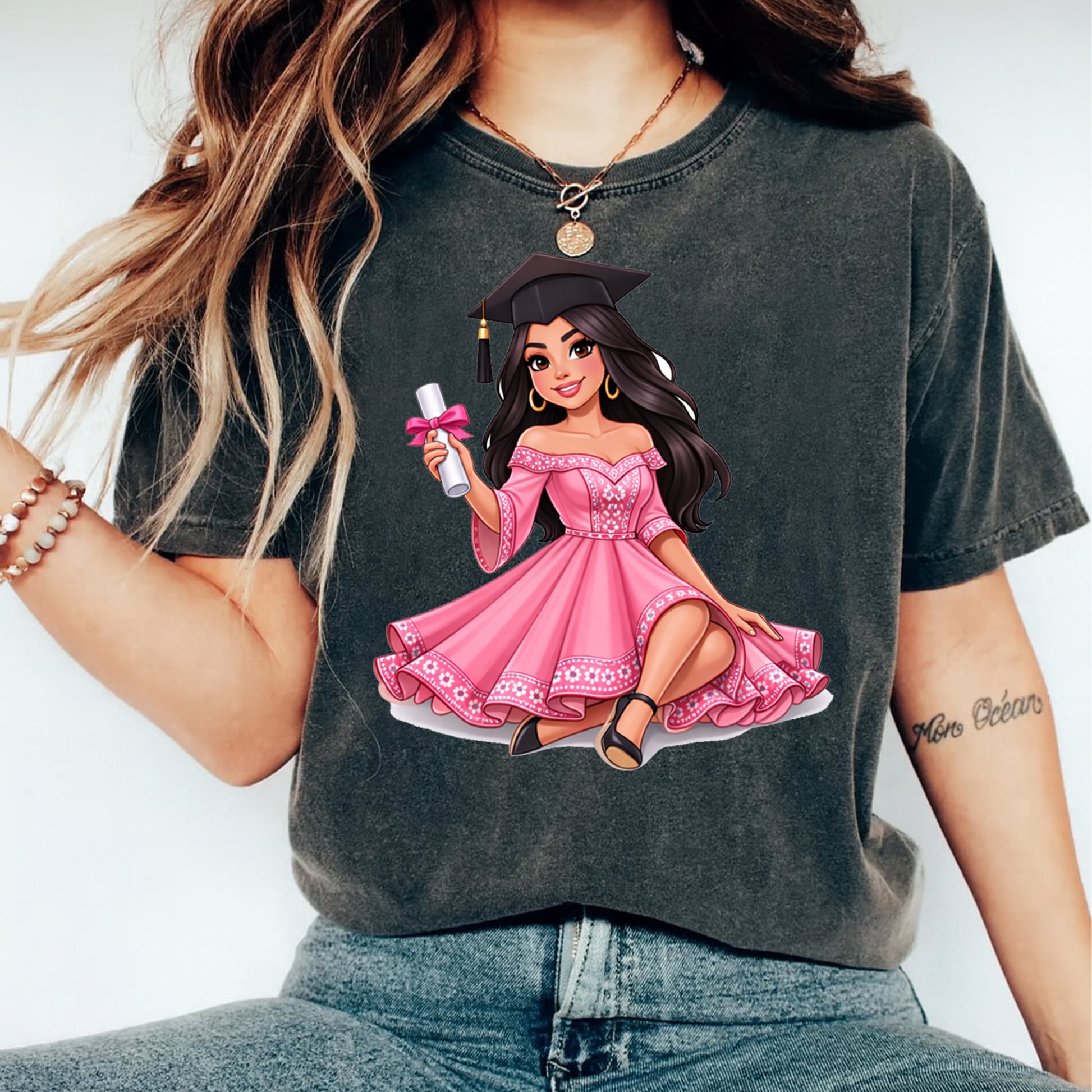 Person wearing a t-shirt with an illustration of a woman in a pink dress and graduation cap.