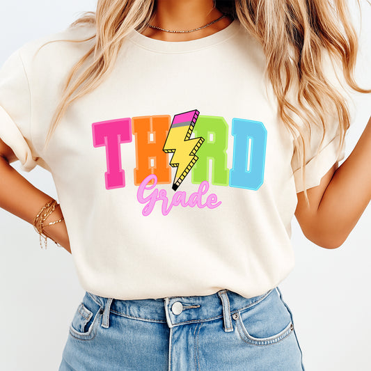Person wearing a white t-shirt with colorful 'THIRD Grade' text design.
