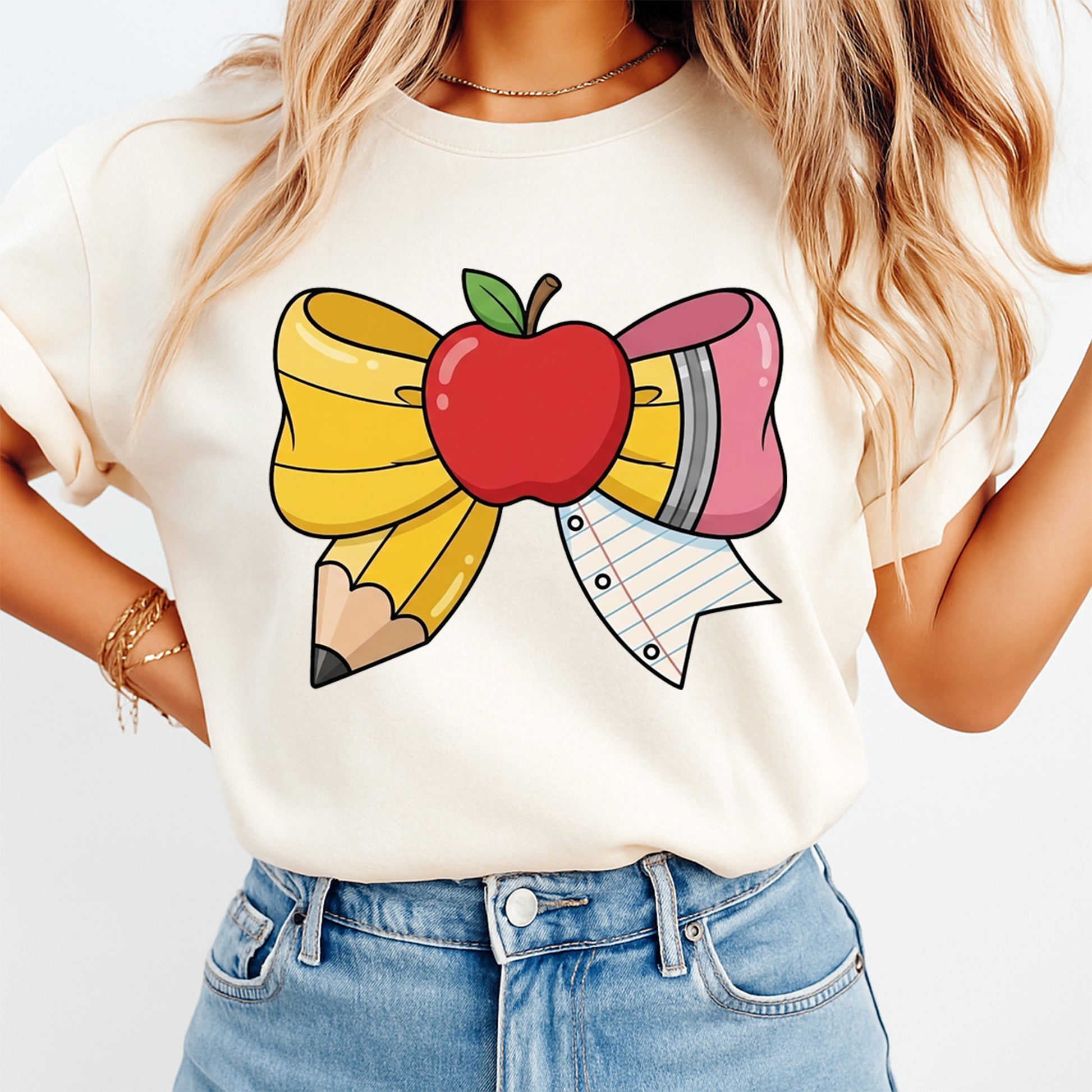 Teacher bow DTF transfer pressed on cream shirt with apple, pencil, eraser, and notebook paper school design