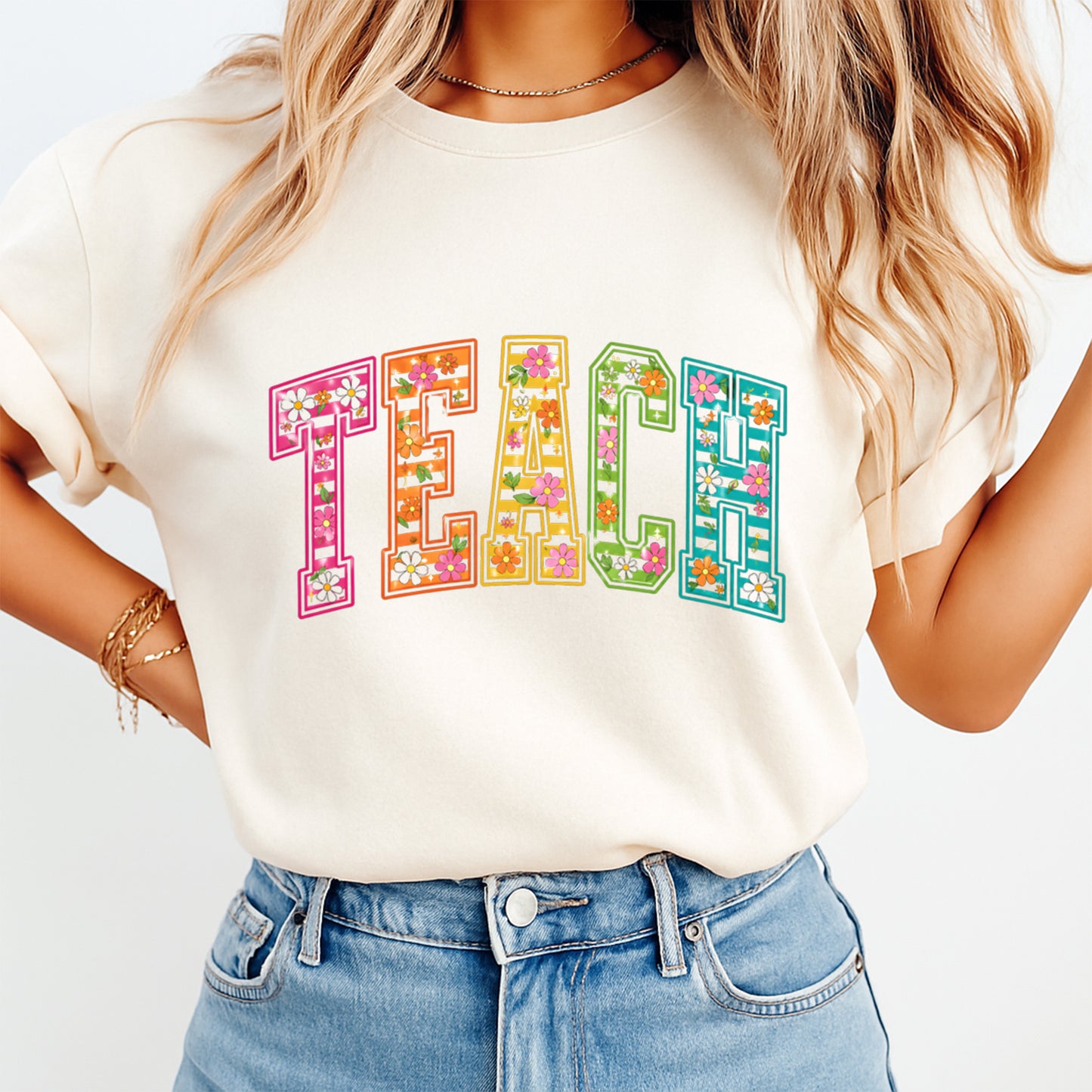 Person wearing a white t-shirt with 'TEACH' in colorful letters and floral designs.