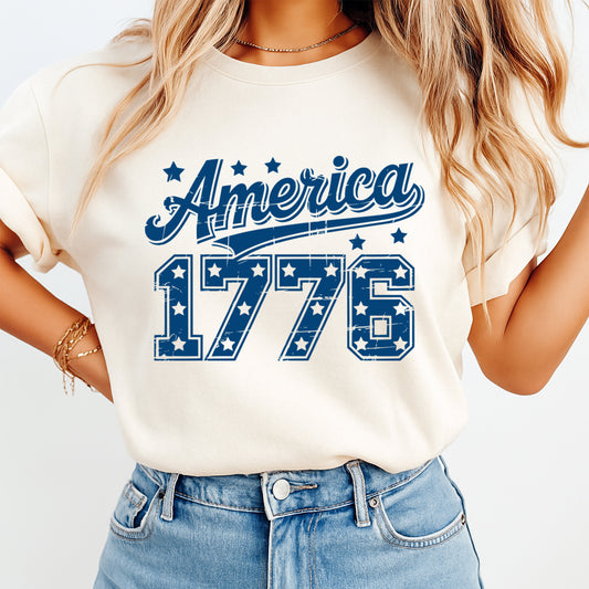 Person wearing a white t-shirt with 'America 1776' design on a plain background