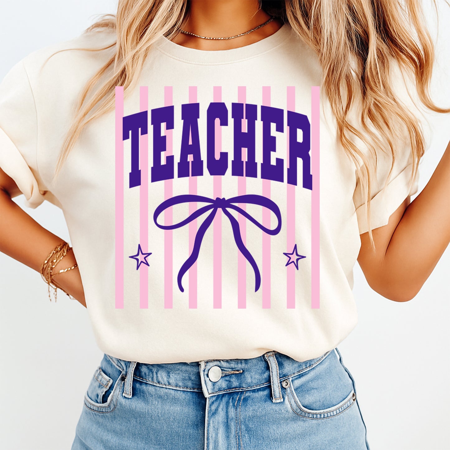 Person wearing a white t-shirt with 'TEACHER' and a bow design on a plain background