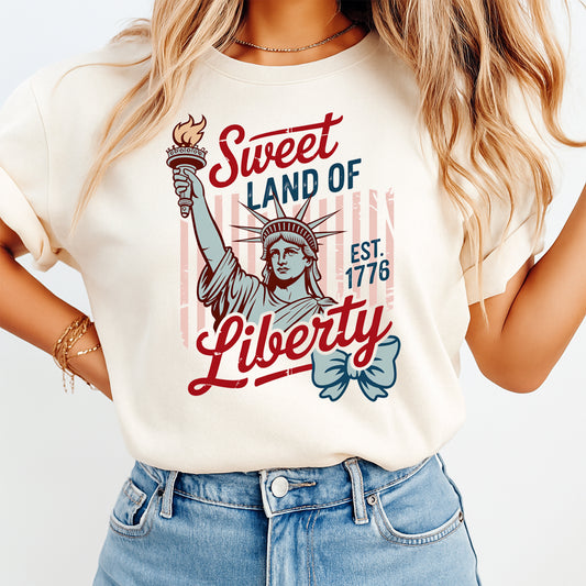 Woman wearing cream shirt with Sweet Land of Liberty patriotic Lady Liberty DTF transfer design