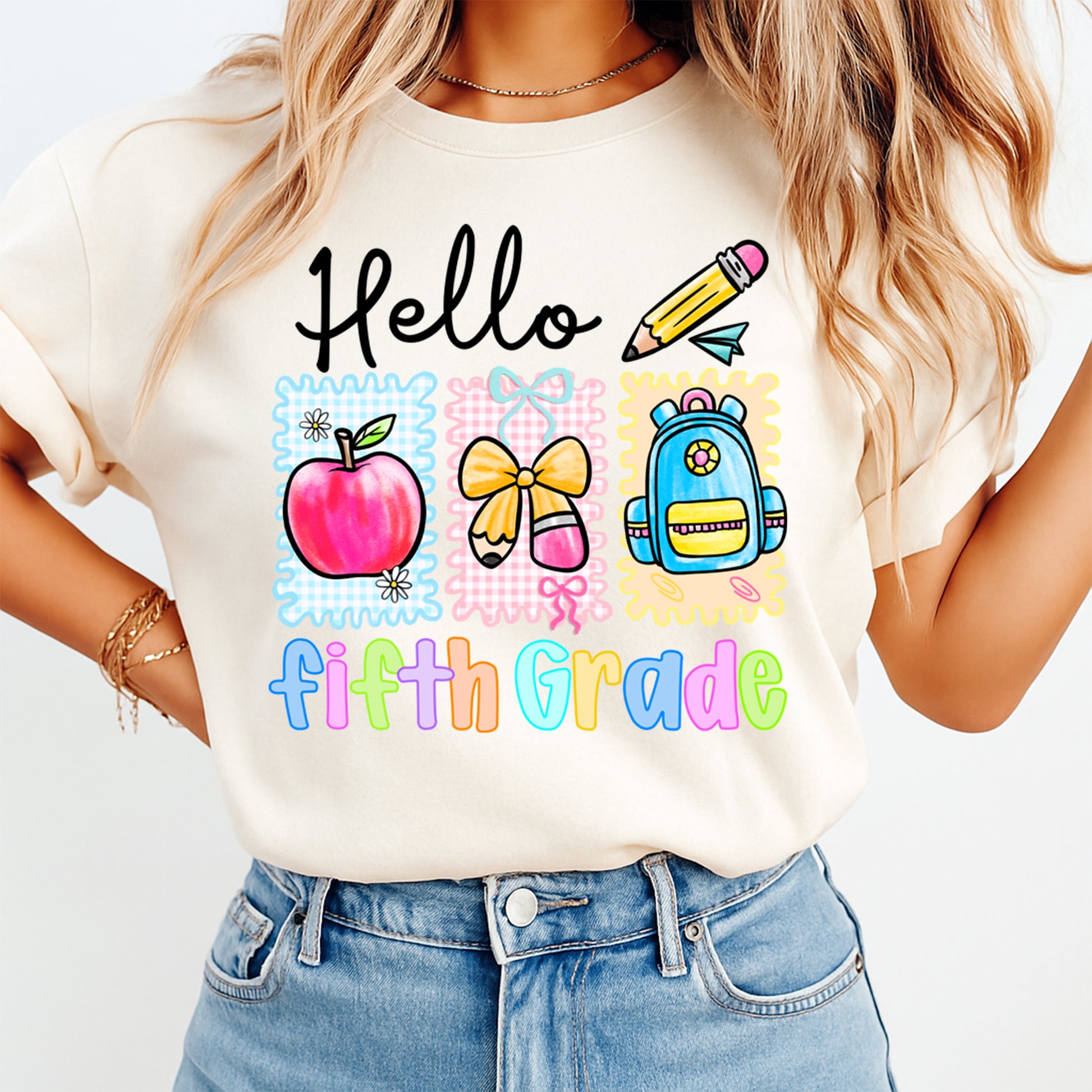 Person wearing a white t-shirt with 'Hello First Grade' design featuring an apple, bow, and backpack.