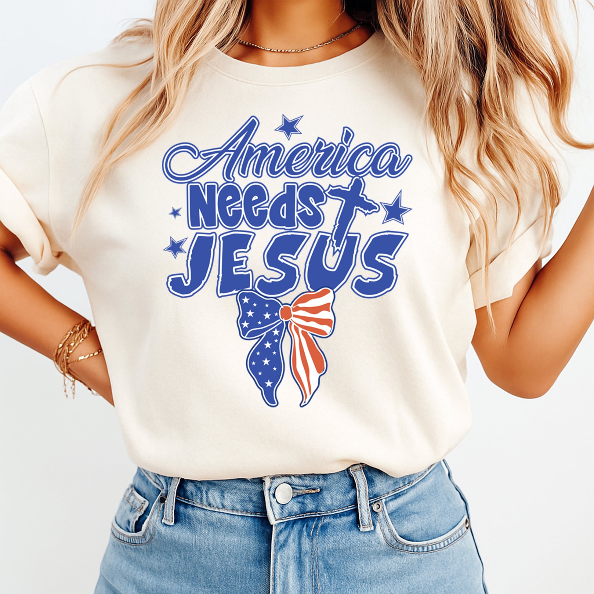 Woman wearing cream shirt with Fourth of July America Needs Jesus DTF transfer featuring patriotic bow and cross design