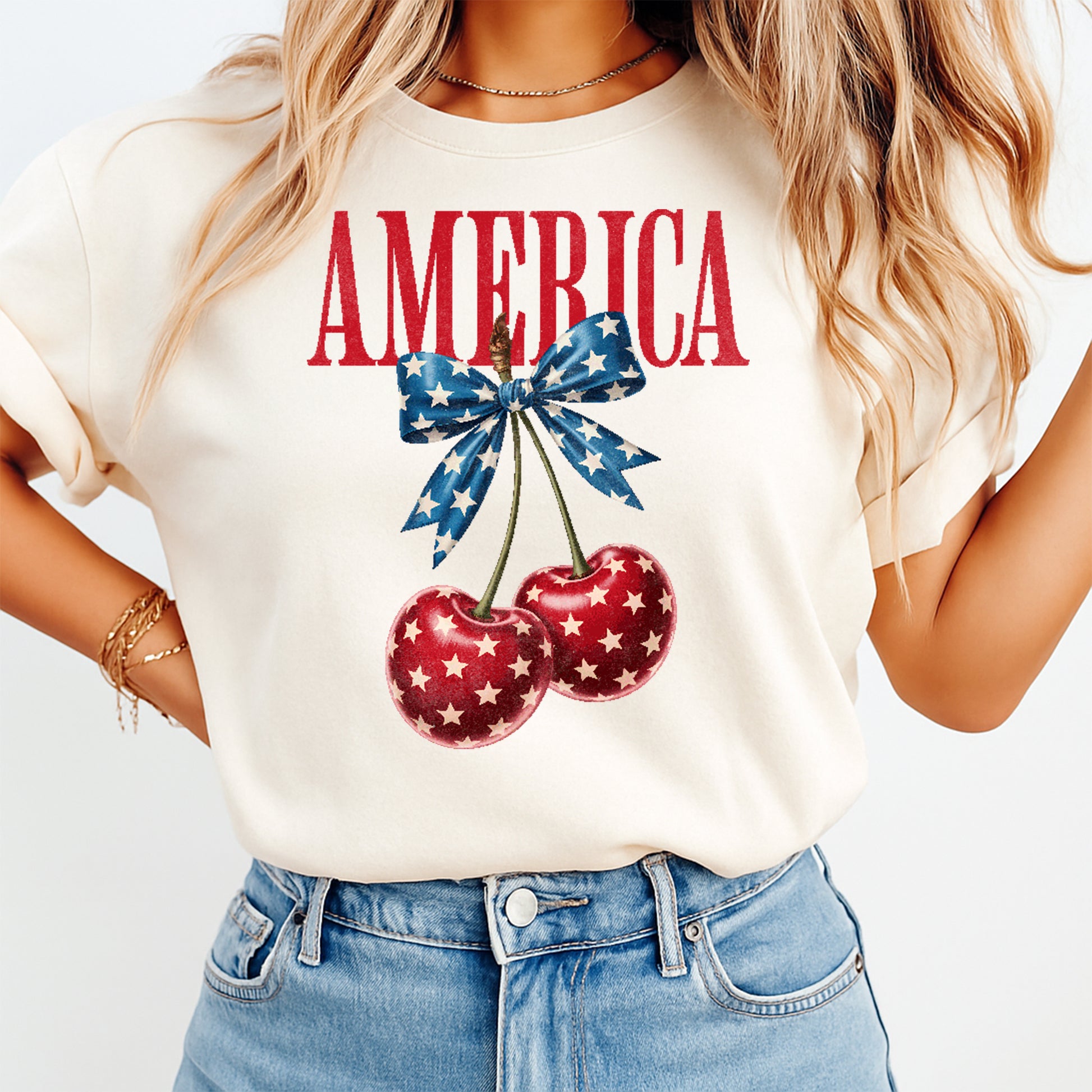 Woman wearing cream shirt with Fourth of July America cherry bow DTF transfer featuring patriotic cherries and blue star bow