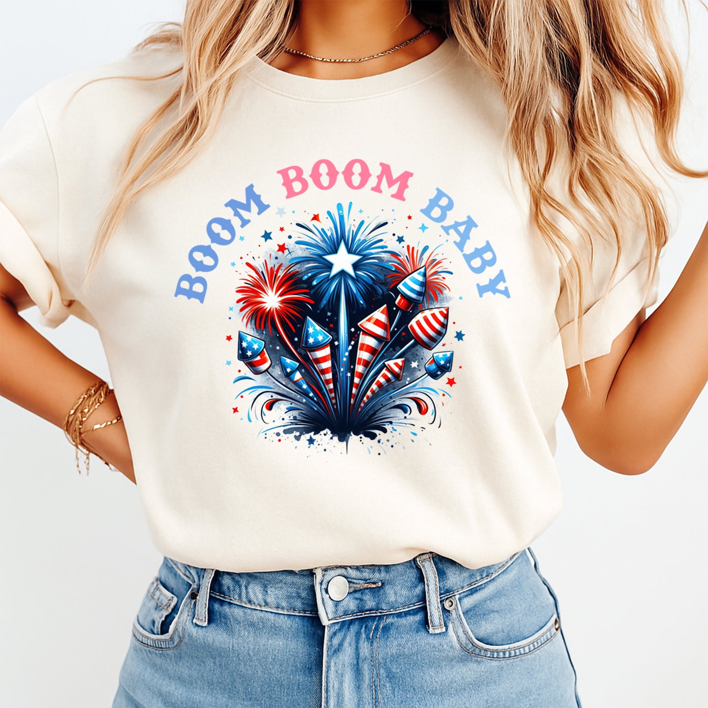 Woman wearing cream shirt with Fourth of July Boom Boom Baby DTF transfer featuring patriotic fireworks and rockets