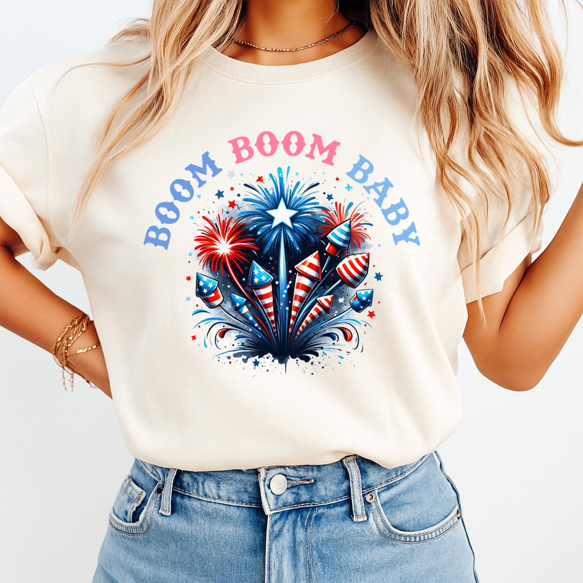 Woman wearing cream shirt with Fourth of July Boom Boom Baby DTF transfer featuring patriotic fireworks and rockets