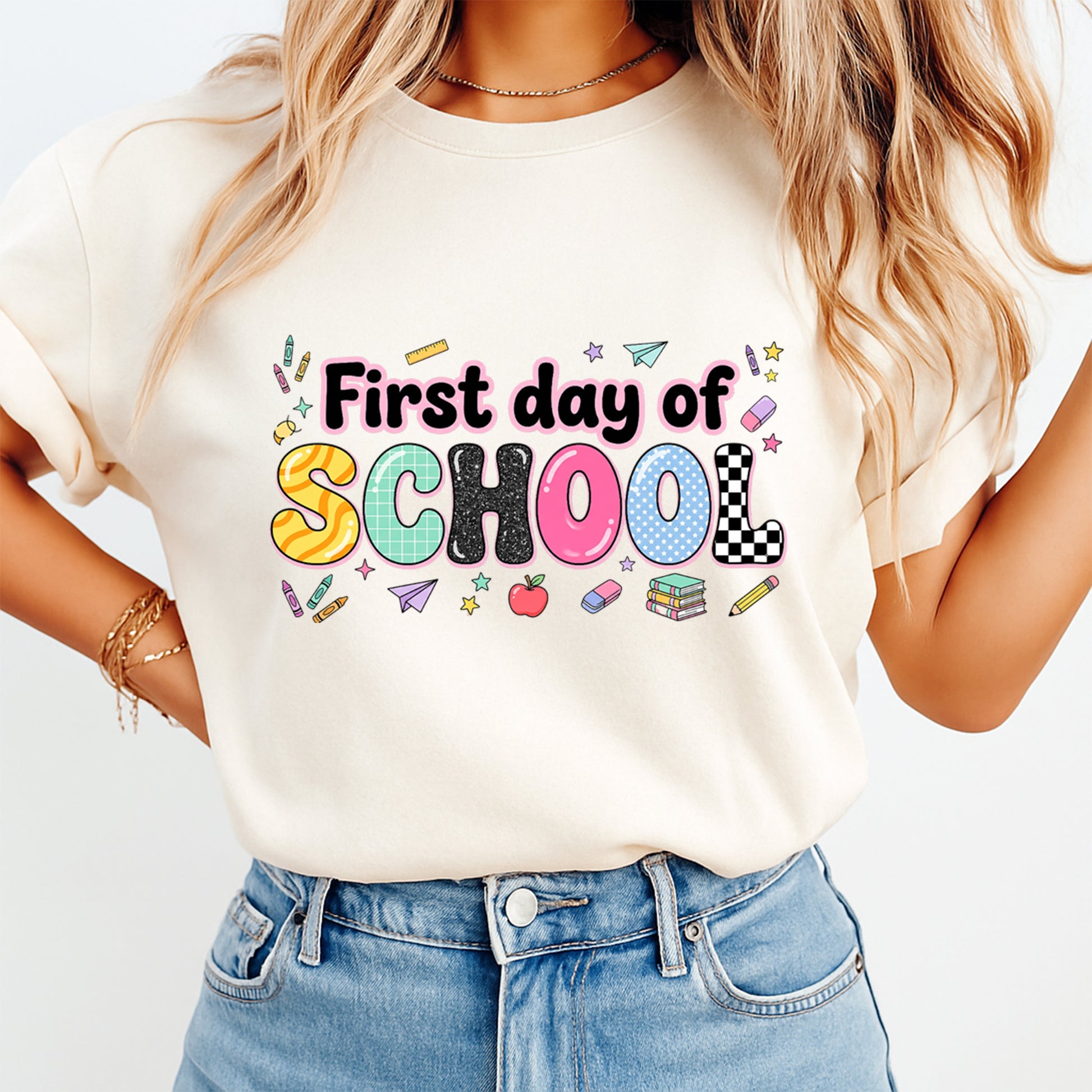 Person wearing a white t-shirt with 'First day of School' text and colorful graphics.