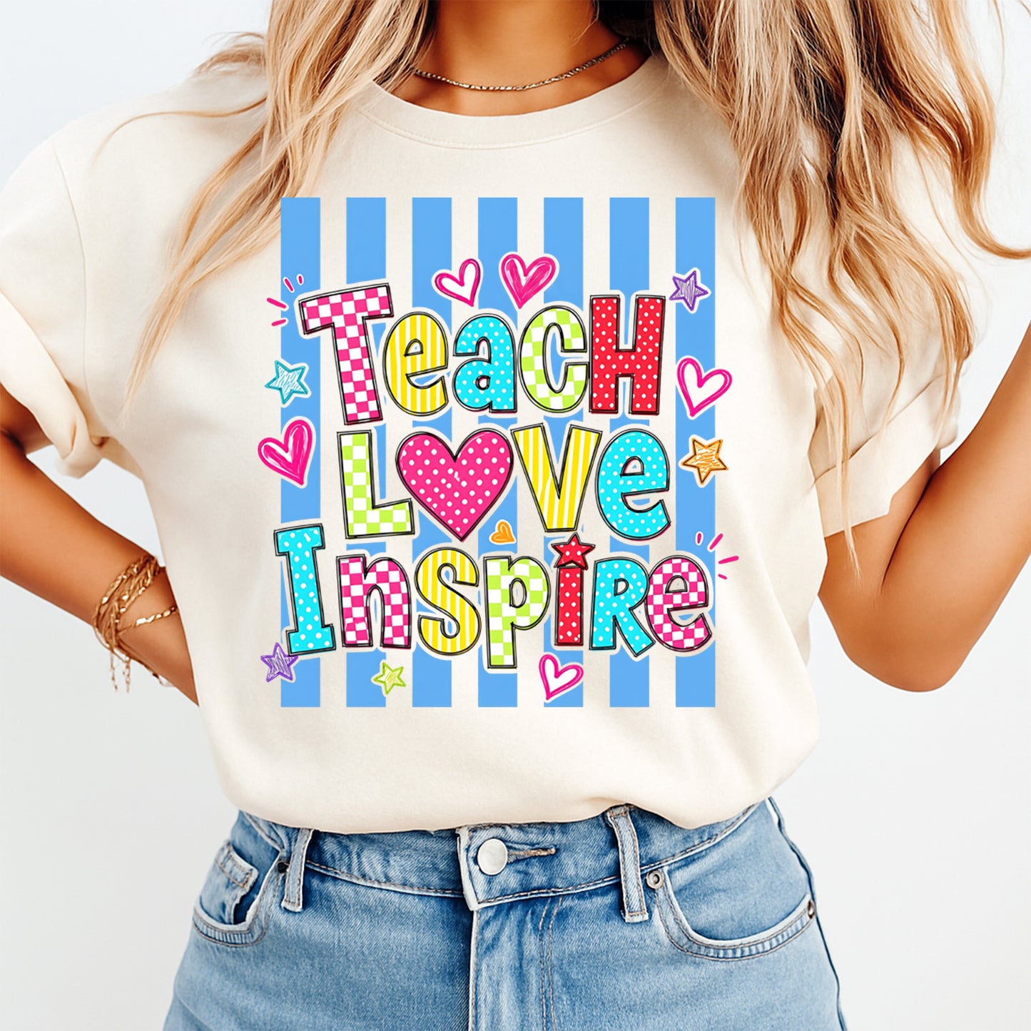 Person wearing a t-shirt with 'Teach Love Inspire' text and colorful design.