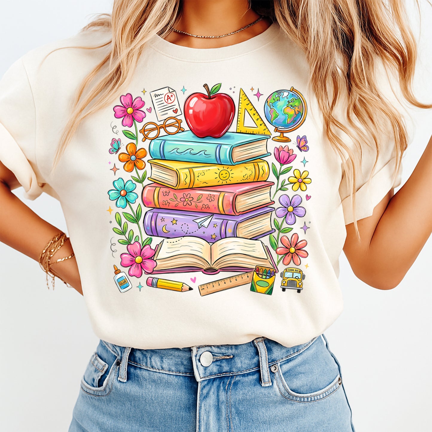 Person wearing a white t-shirt with colorful book and school supplies design.